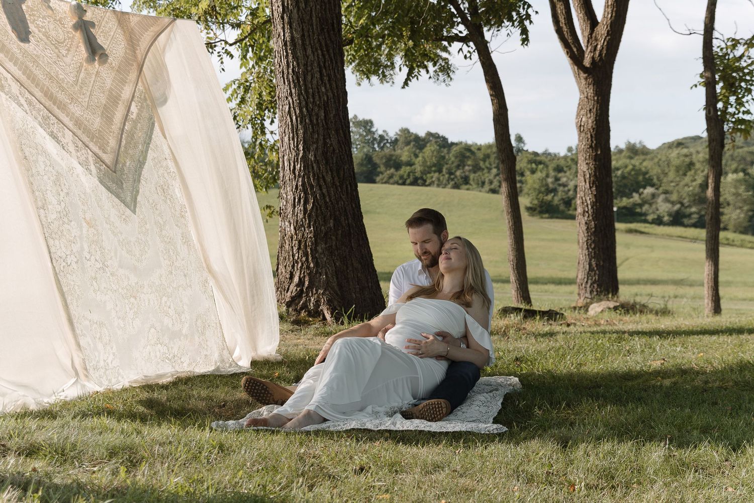 couple sitting under a tree leaning into one another