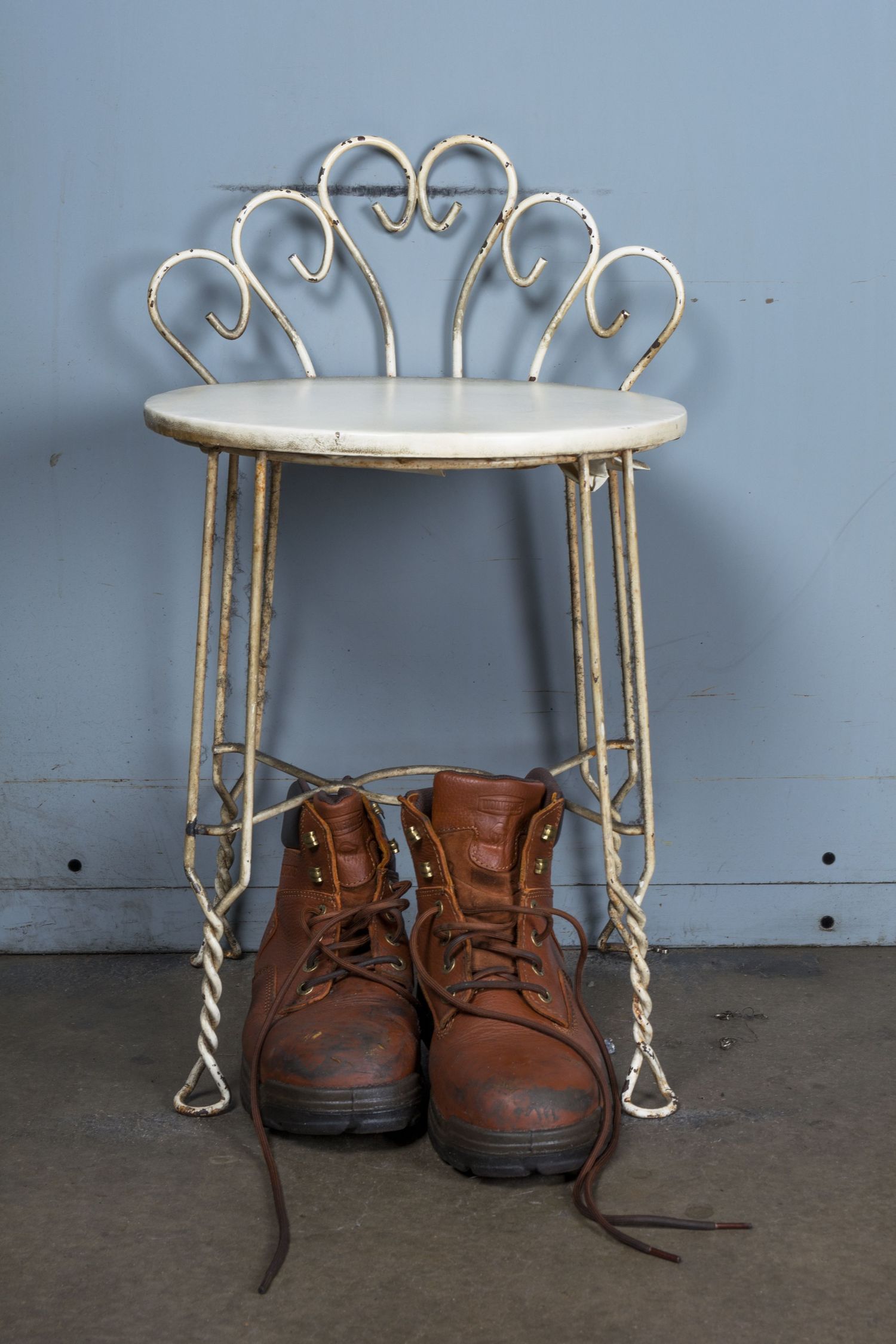 Brown leather work boots placed under decorative white metal stand.