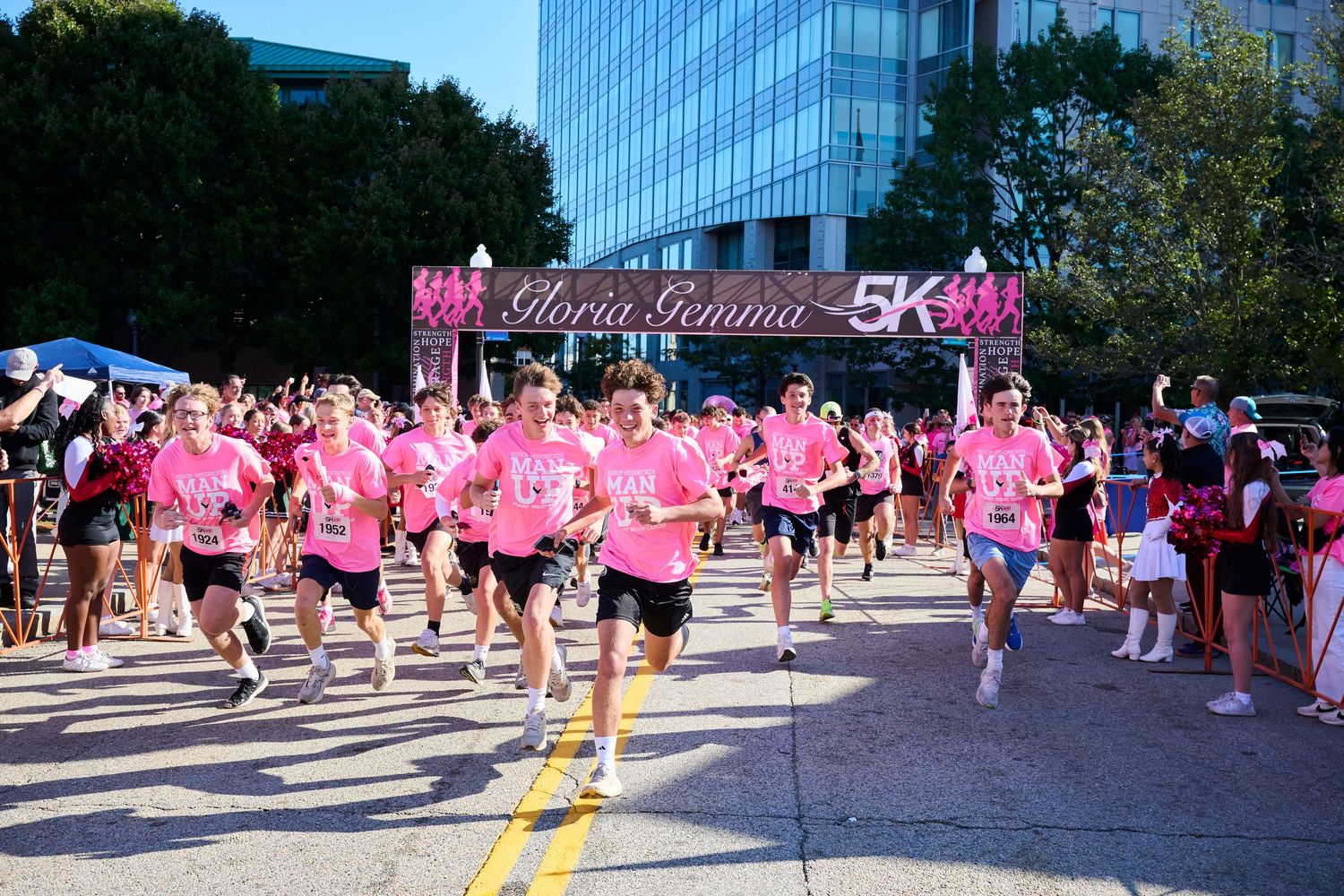 Large crowd of runners in pink shirts participate in a breast cancer awareness 5K race.