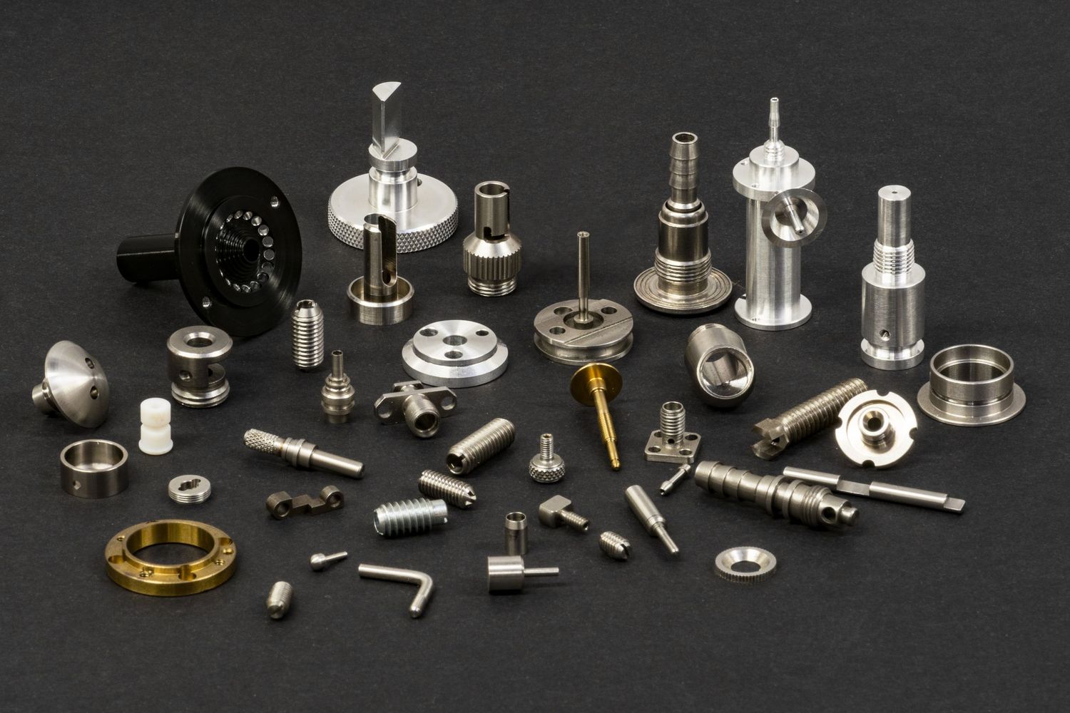 Collection of precision machined metal parts and components displayed on dark background.