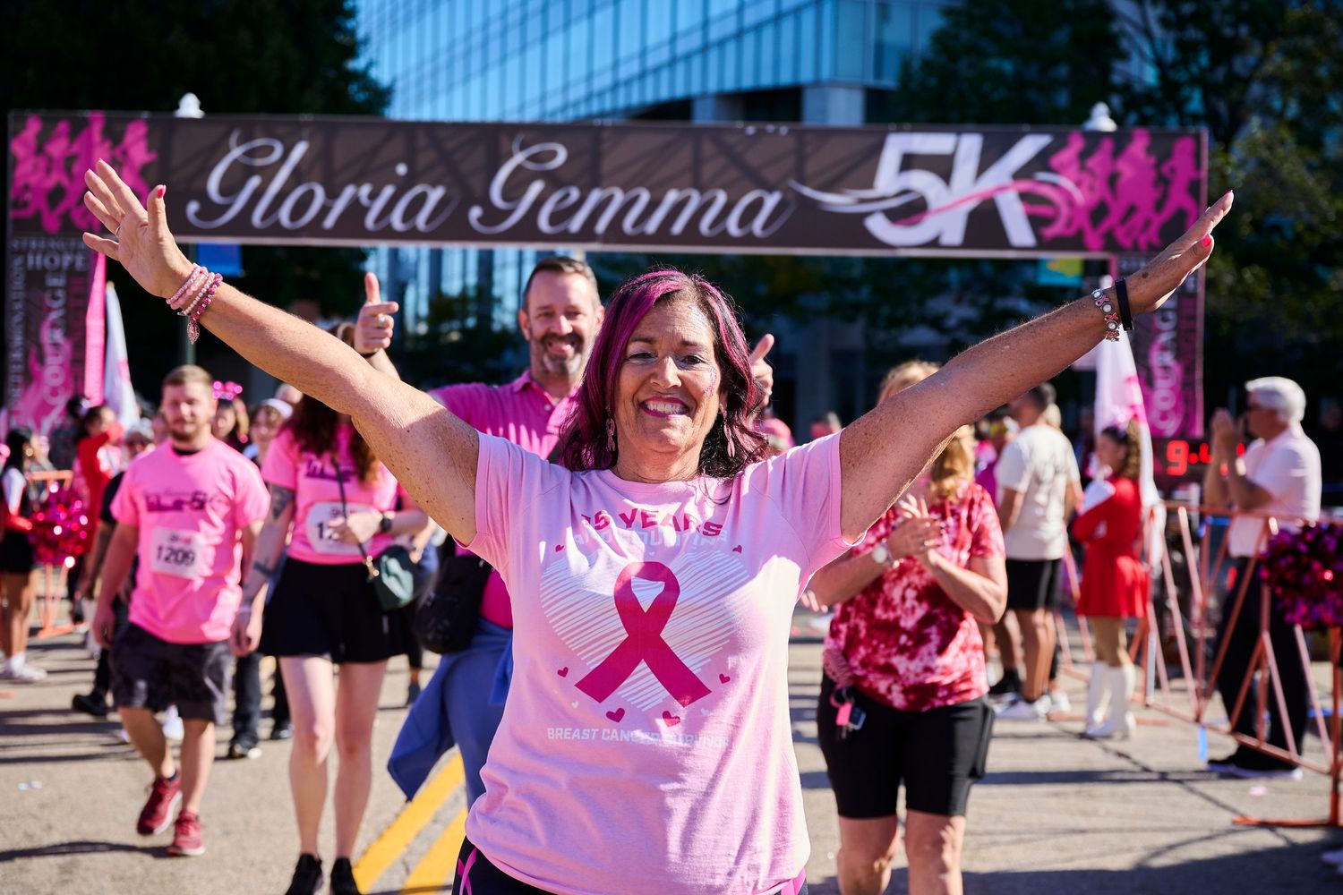 Enthusiastic participant celebrates at the Gloria Gemma 5K finish line wearing pink.