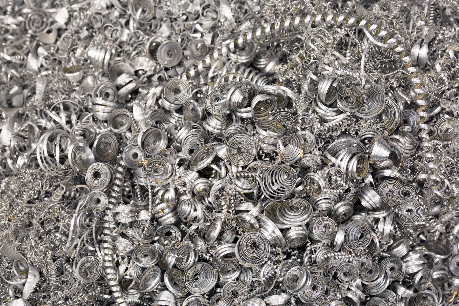 Close-up view of assorted metal machine parts and gears creating an industrial pattern.