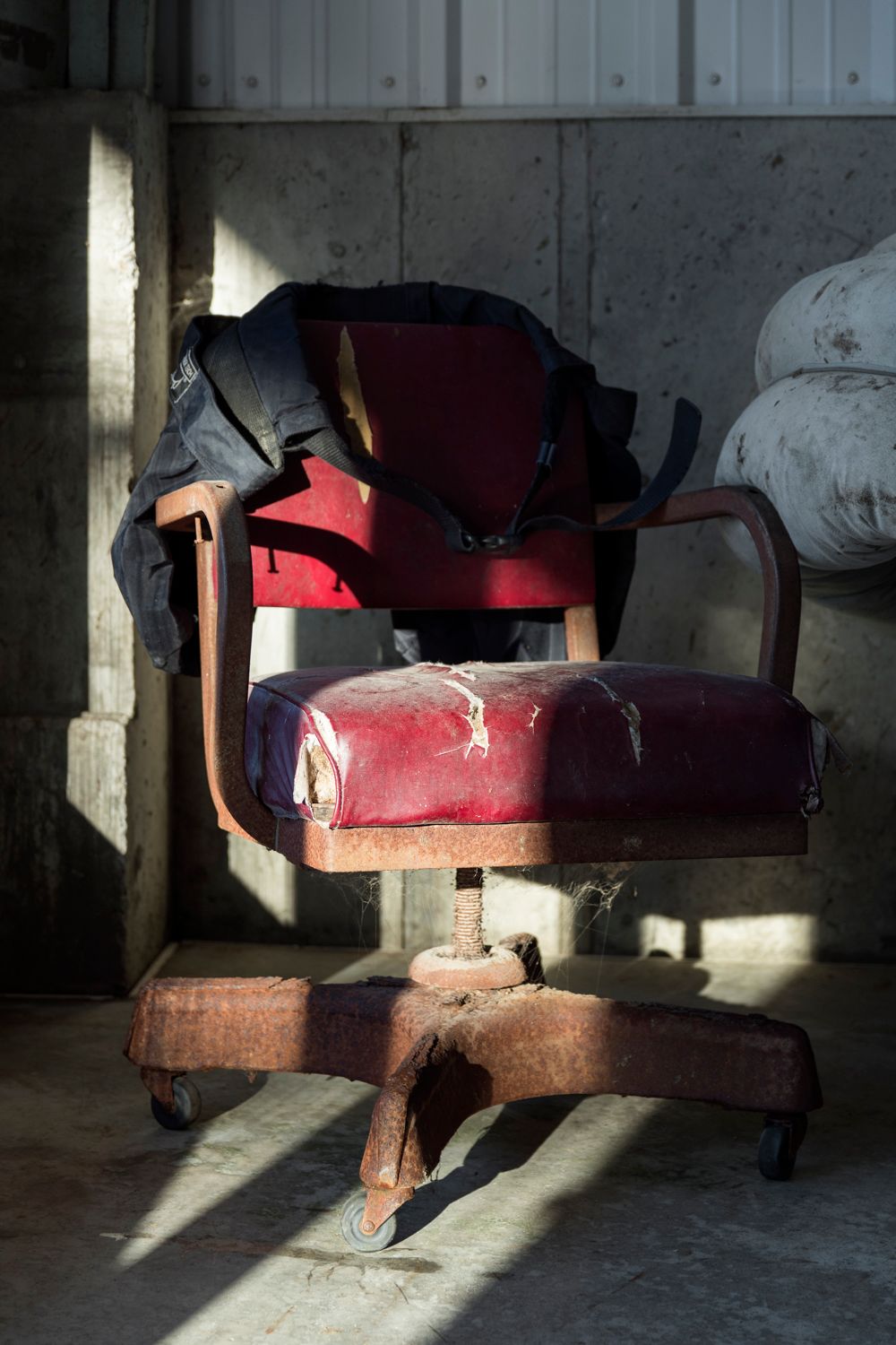 Old red cushioned seats in dark room with dramatic shadows.
