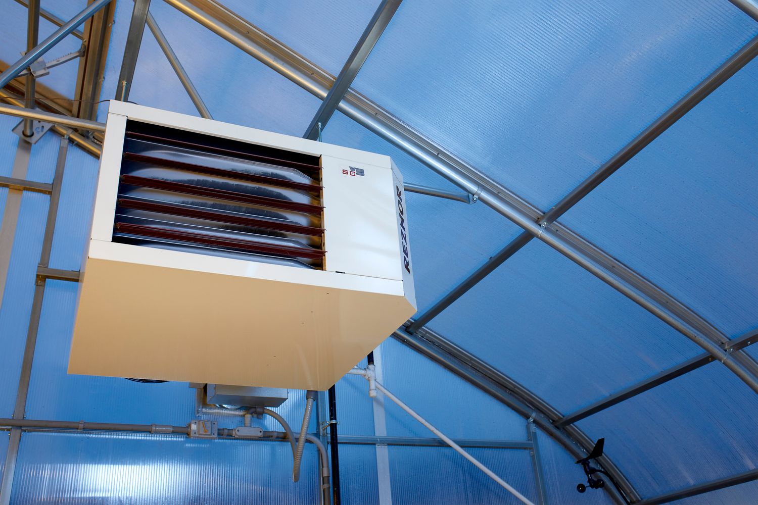 Industrial greenhouse ventilation system with metal frames and glass panels in blue sky.