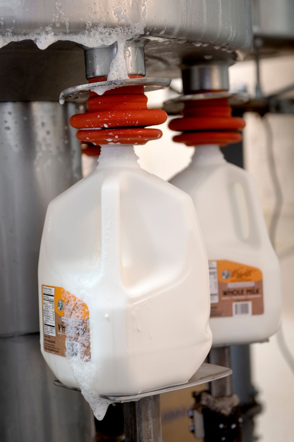 White plastic containers with orange labels mounted under metal dispensing equipment.
