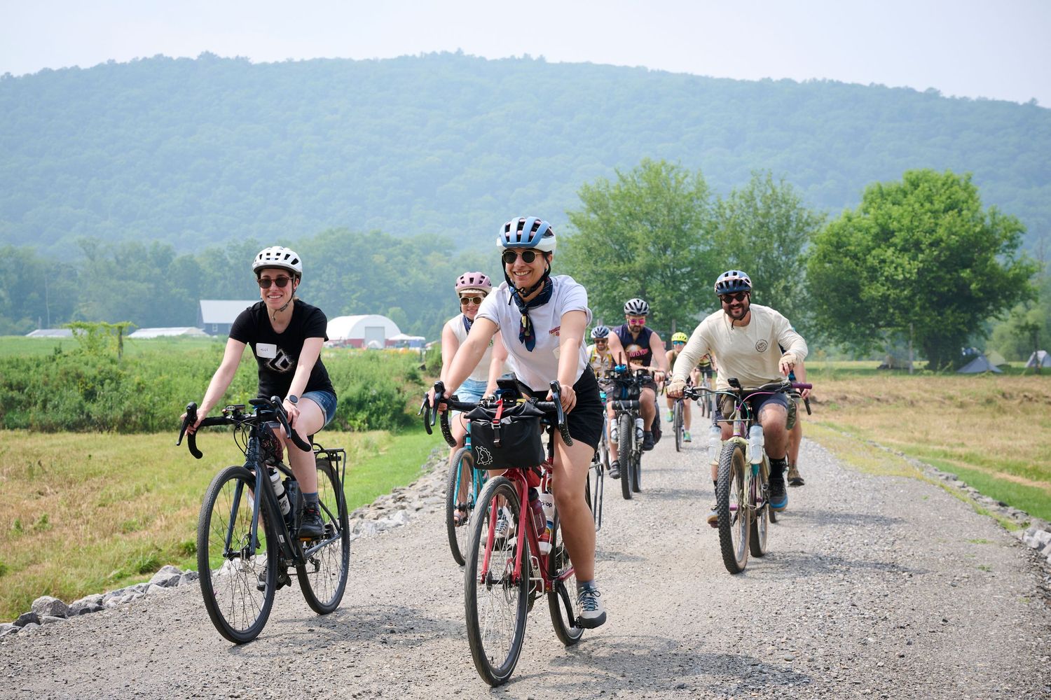 Cyclists traverse a scenic mountain trail during a group ride on a sunny day.