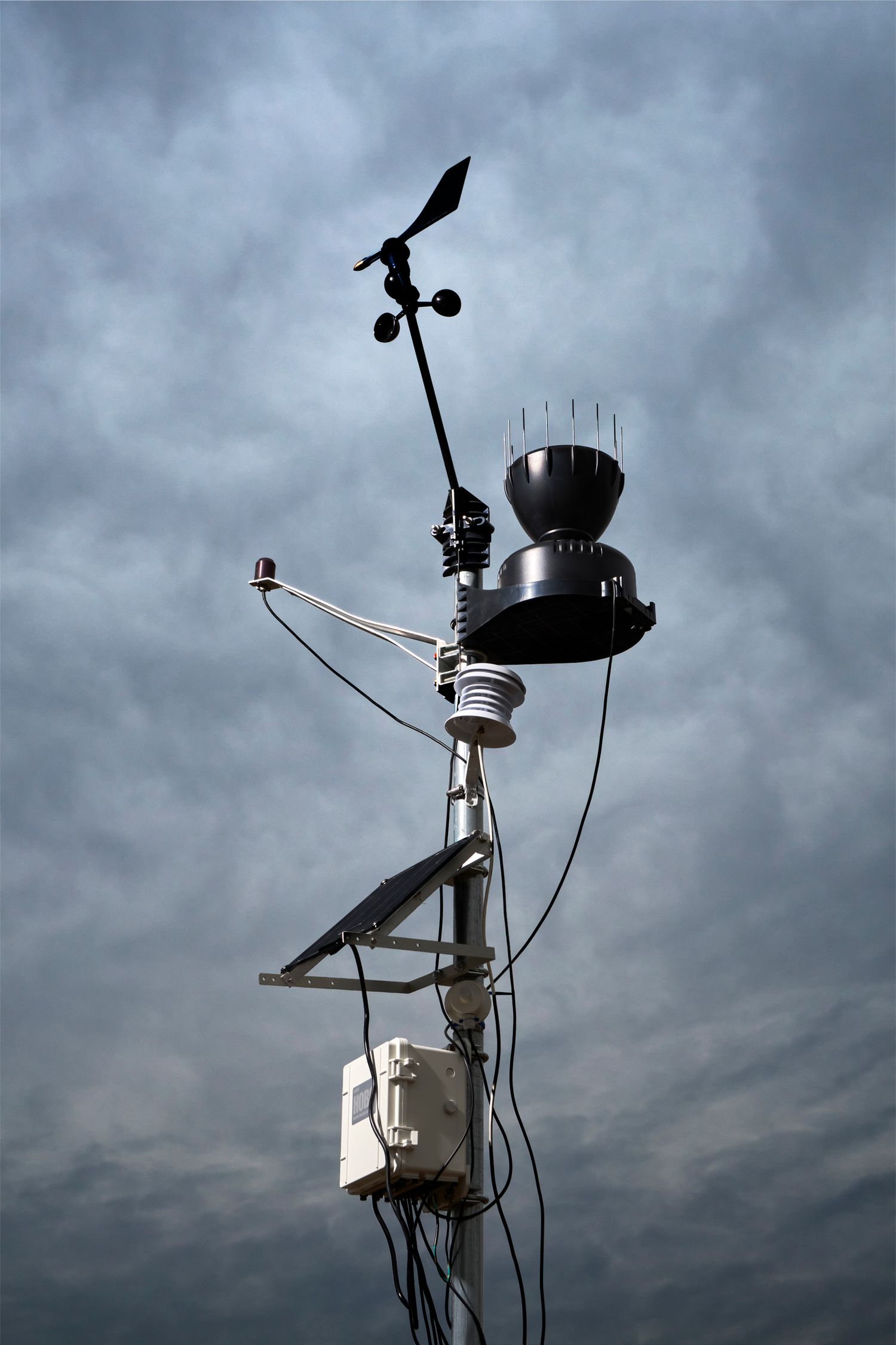 Weather monitoring equipment and instruments silhouetted against a dramatic cloudy sky.