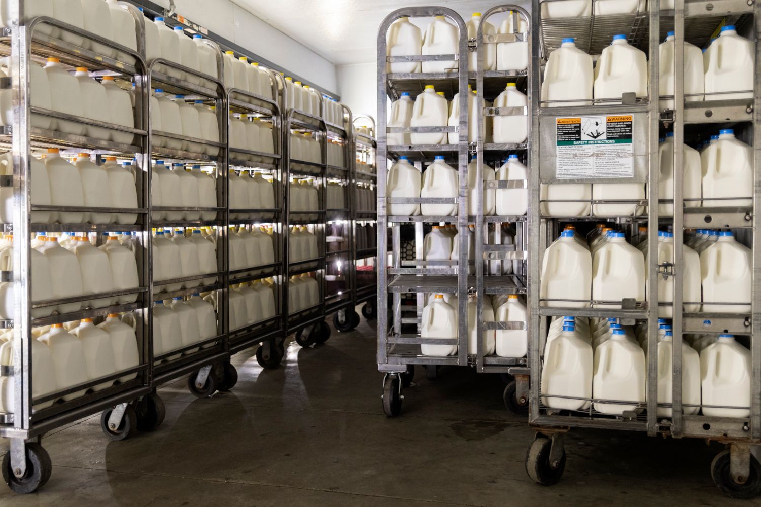 Long rows of white protective garments hanging on industrial clothing racks in a clean room.