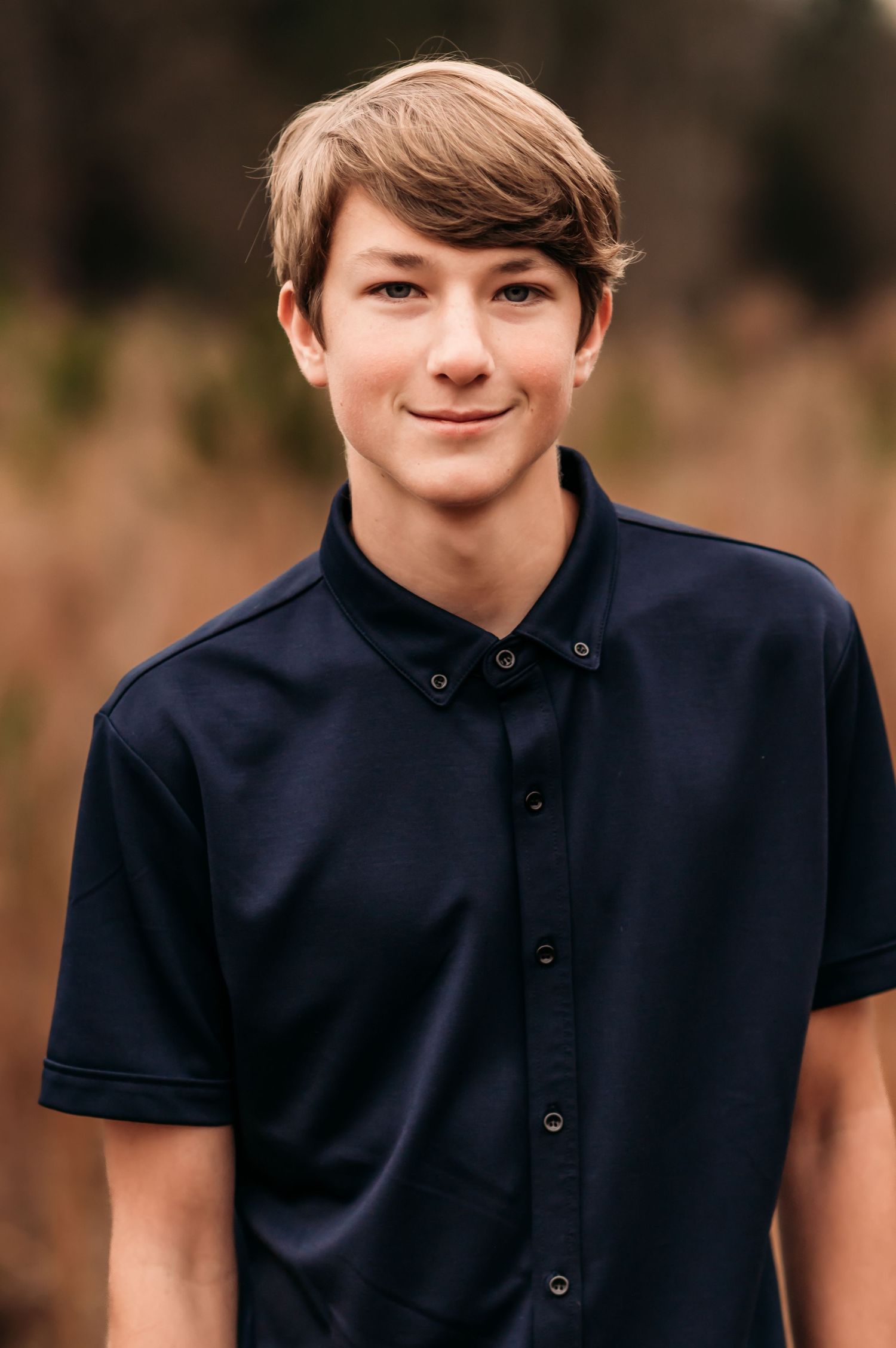 Teenager walking and smirking in a grass field.