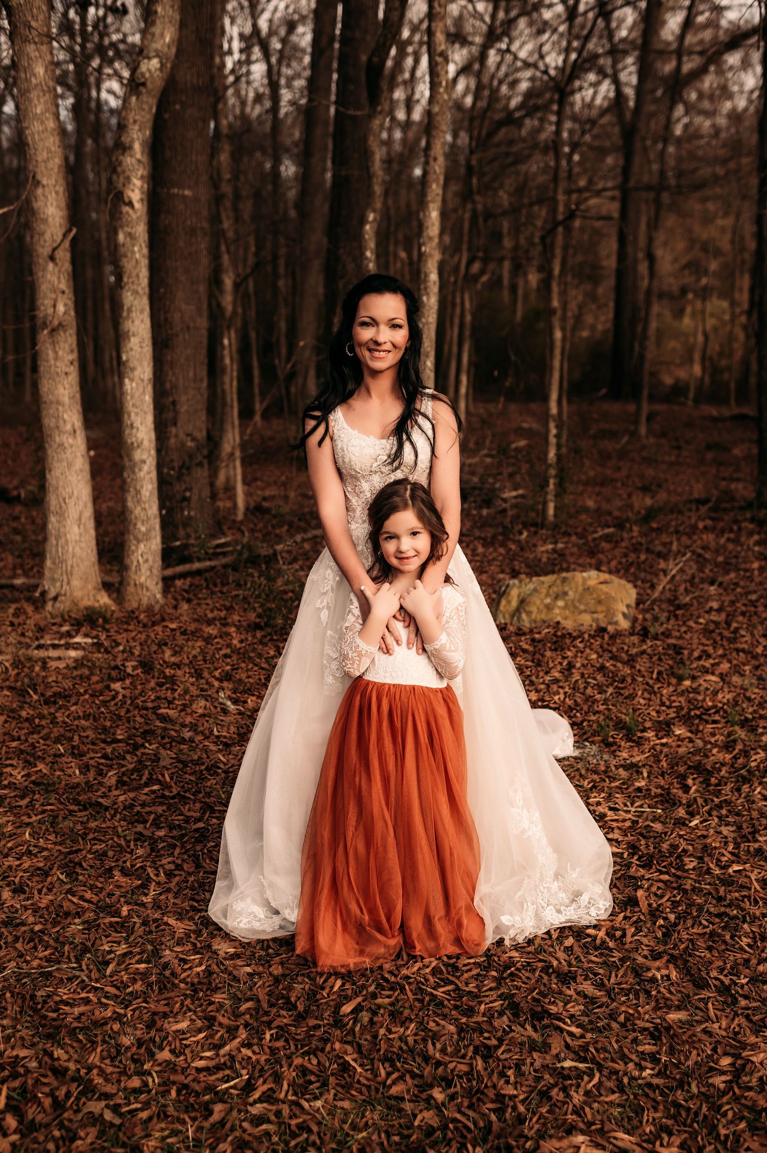 Mother bride with daughter in front of her snuggling her hands.
