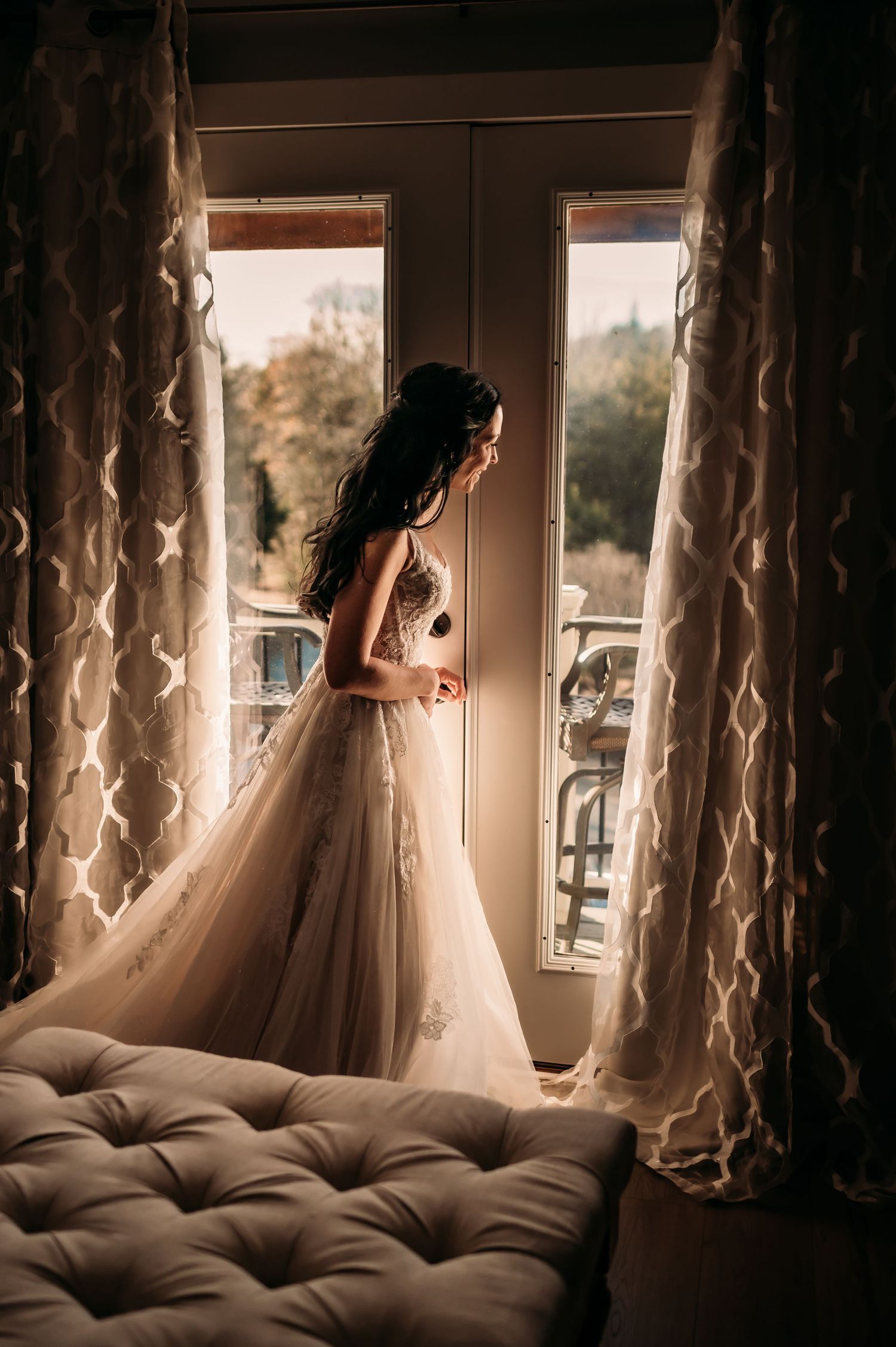 A bride peeks out her window pre-ceremony as guests arrive.