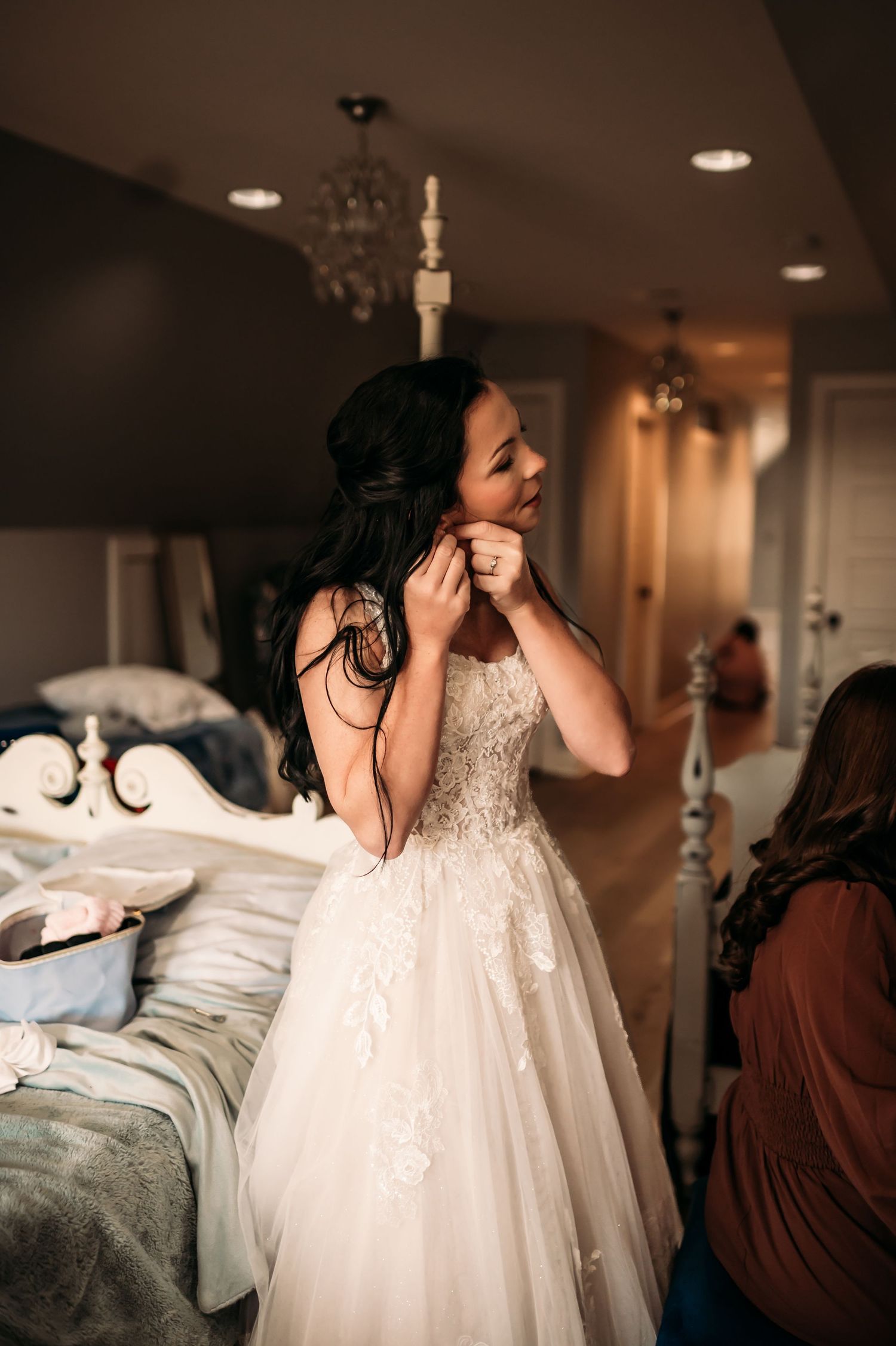 A bride gets ready for her ceremony by looking in a mirror and putting on her earrings.