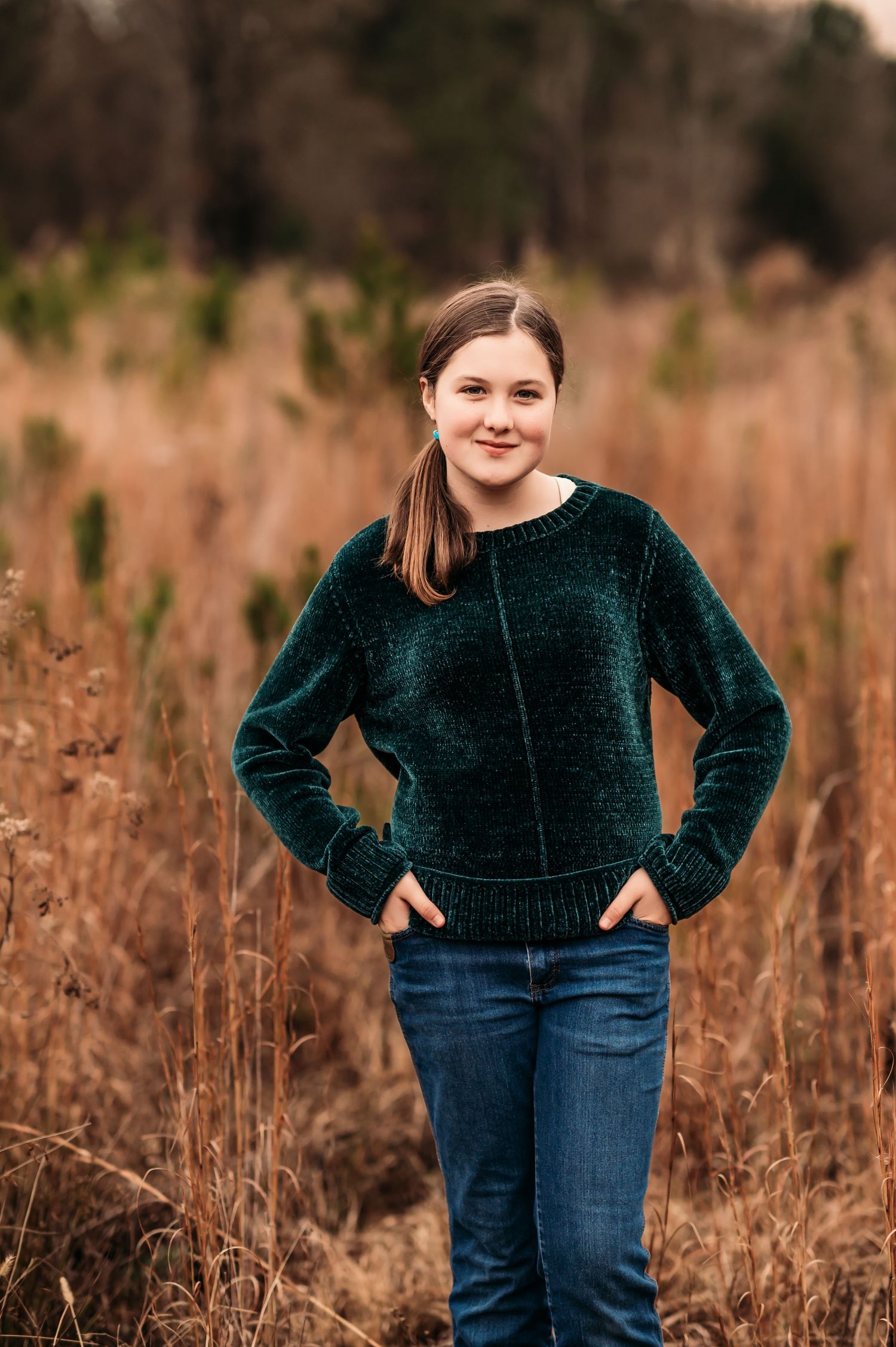 Teenage girl smiling while standing in front of a field of tall grass.