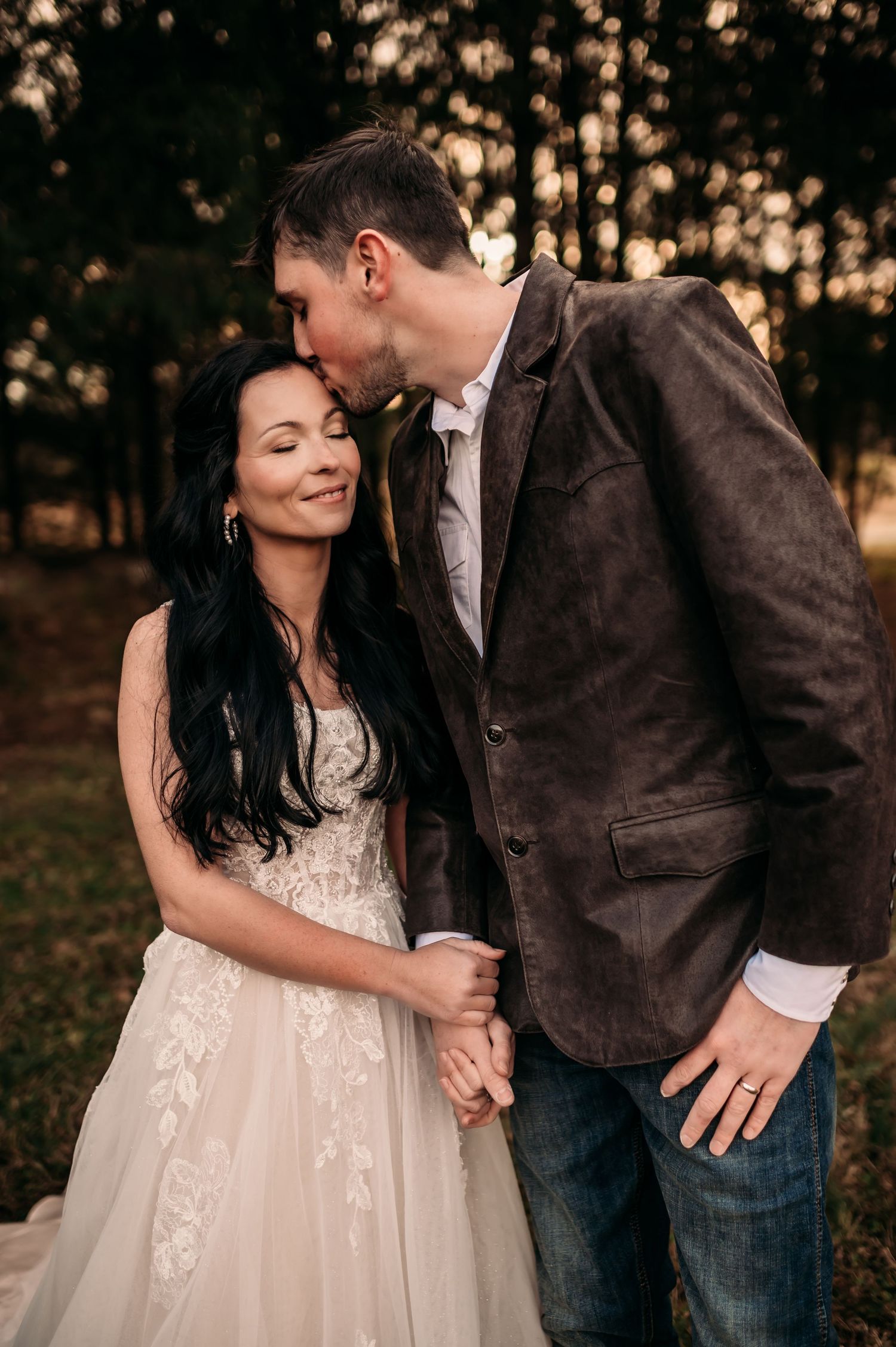 Groom kissing bride on the temple while bride closes her eyes and smiles softly.