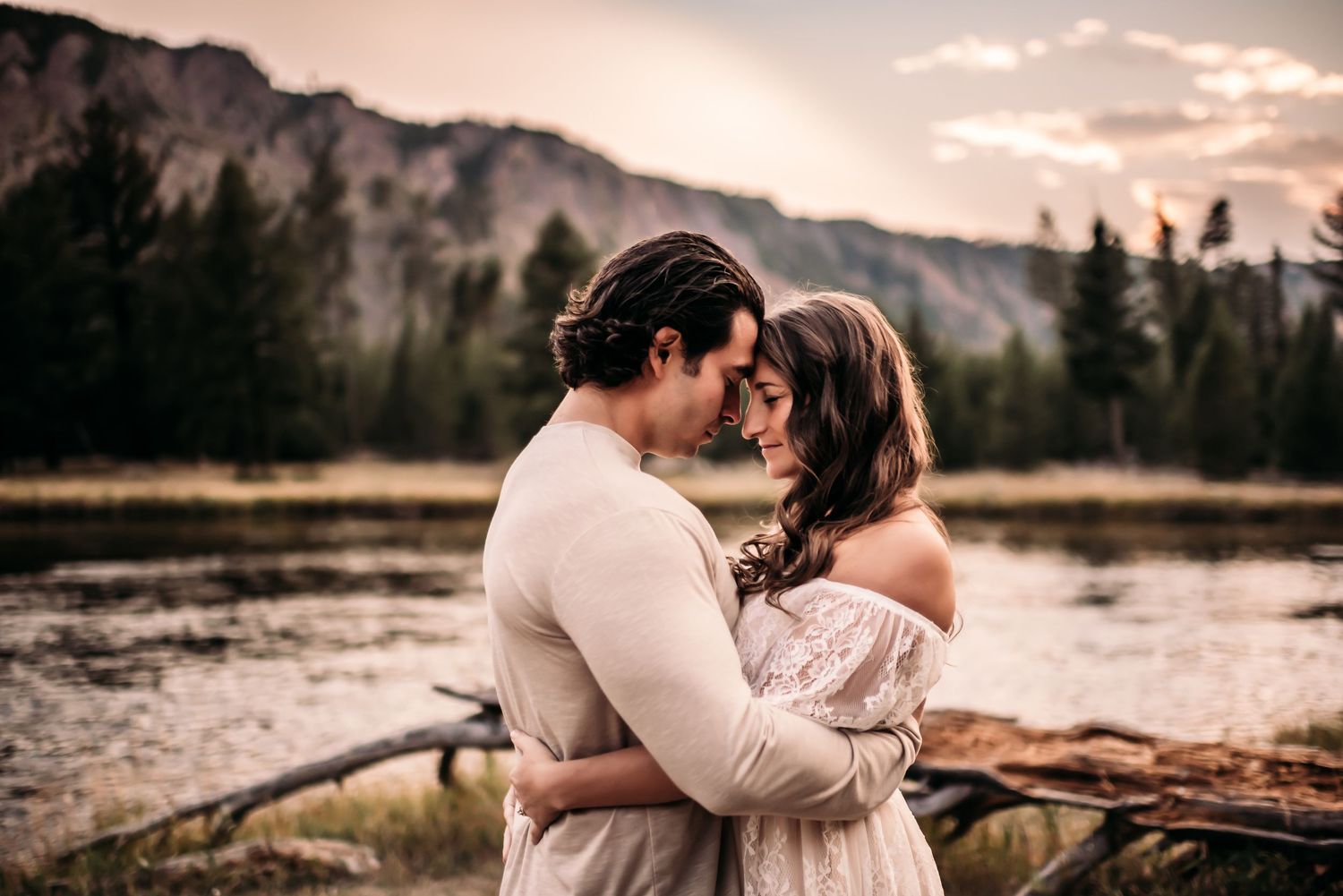 Couple standing head to head in from of mountains and lake.