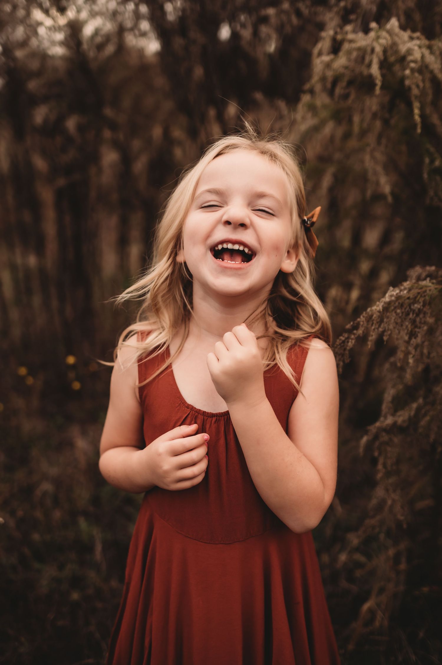 A 5 year old girl laughing and wearing a boho dress.