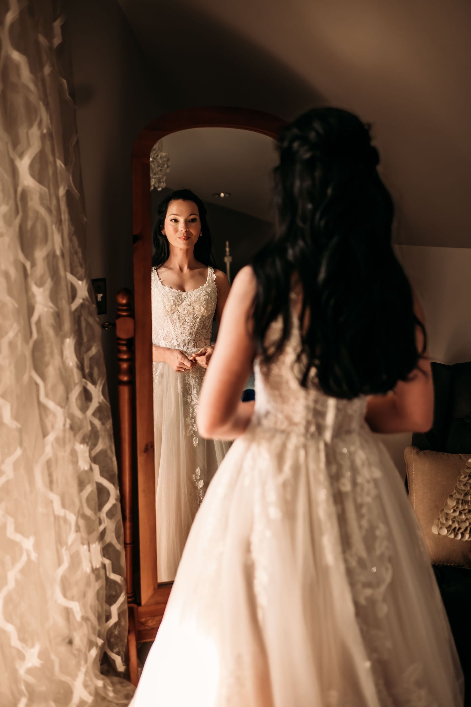 A bride looks in the mirror in her wedding dress.