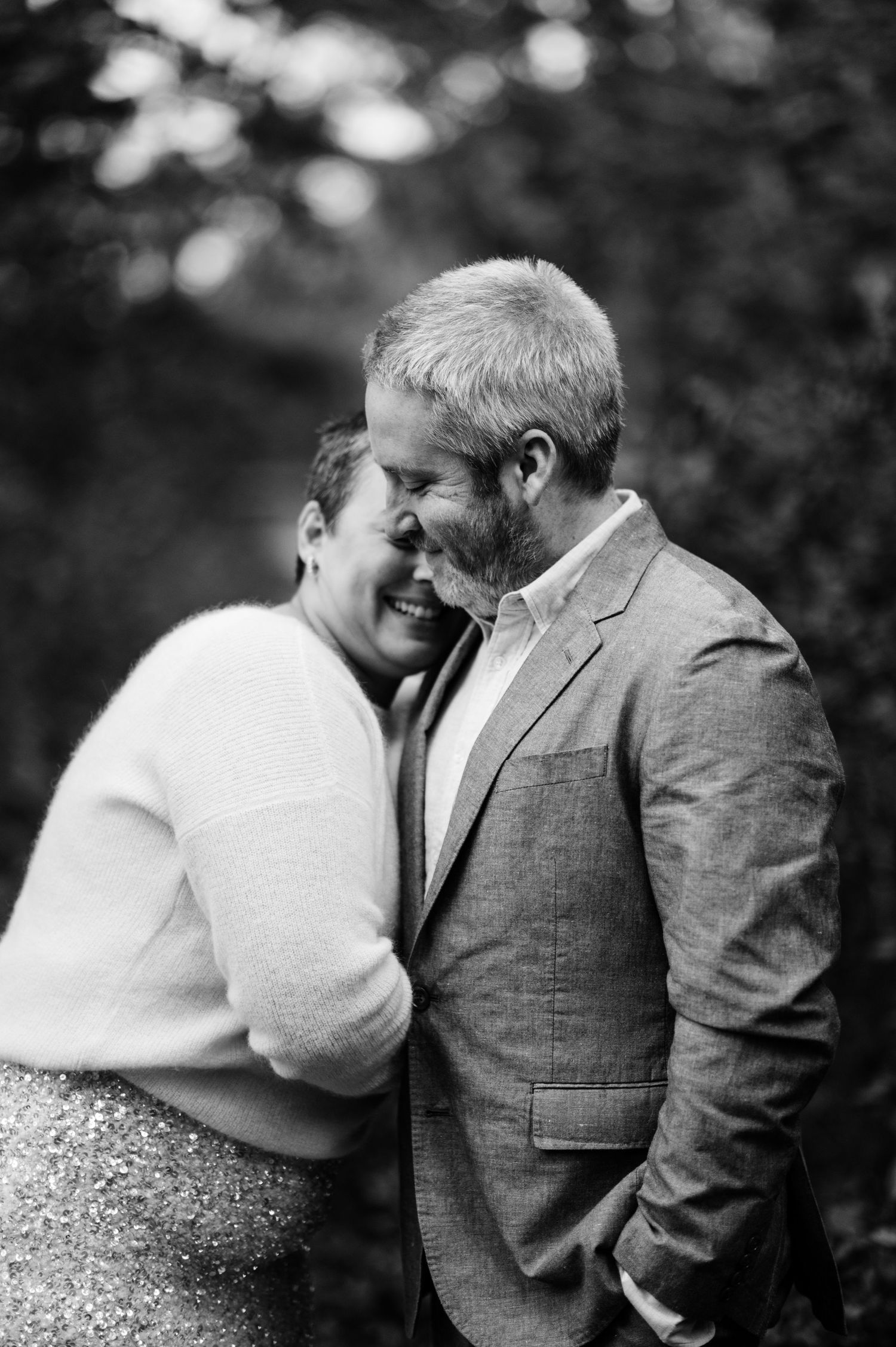 Black and white intimate portrait of a couple sharing a tender moment outdoors.