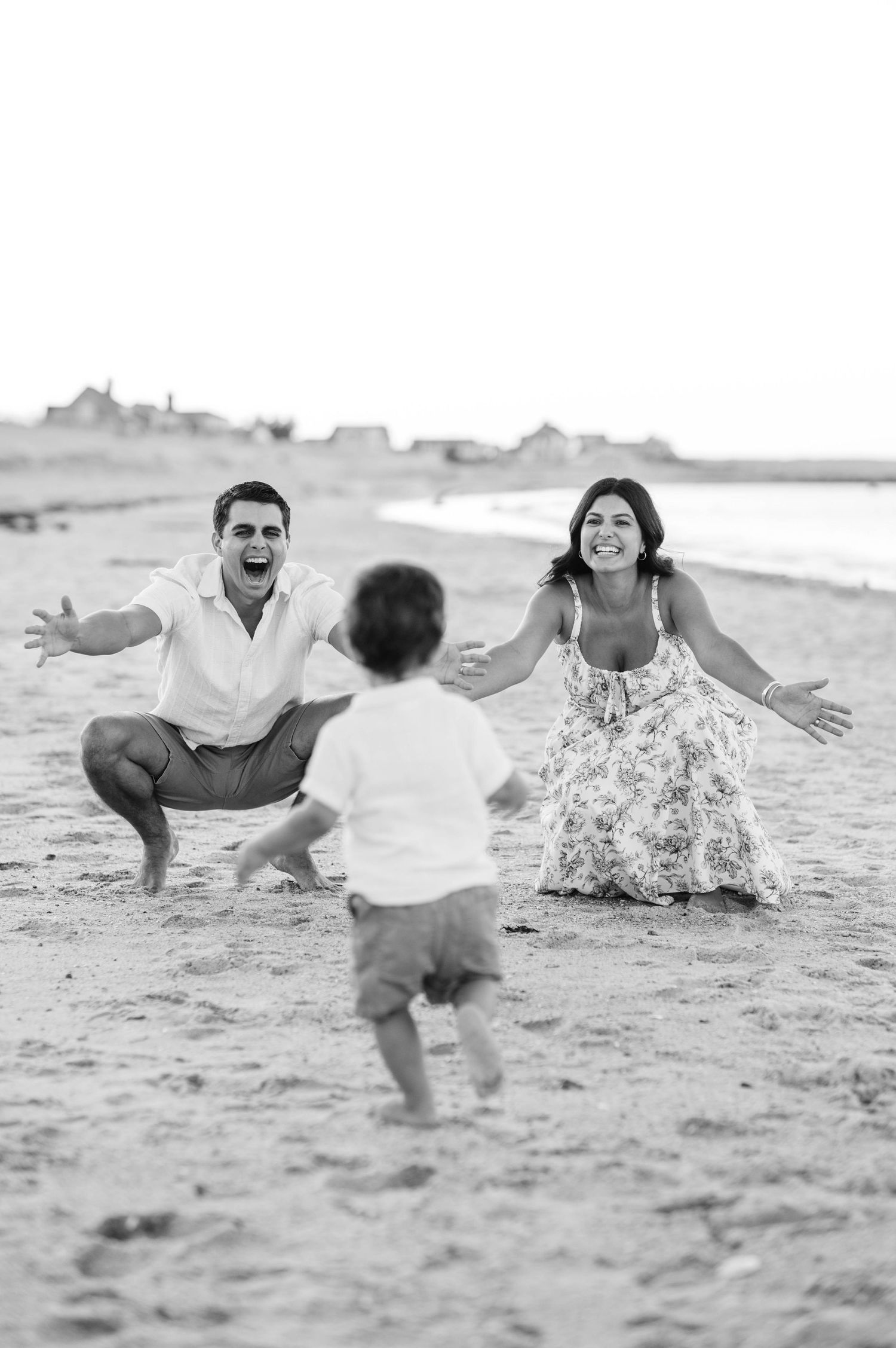 Black and white sequence of a family playing and running towards each other on a sandy beach.