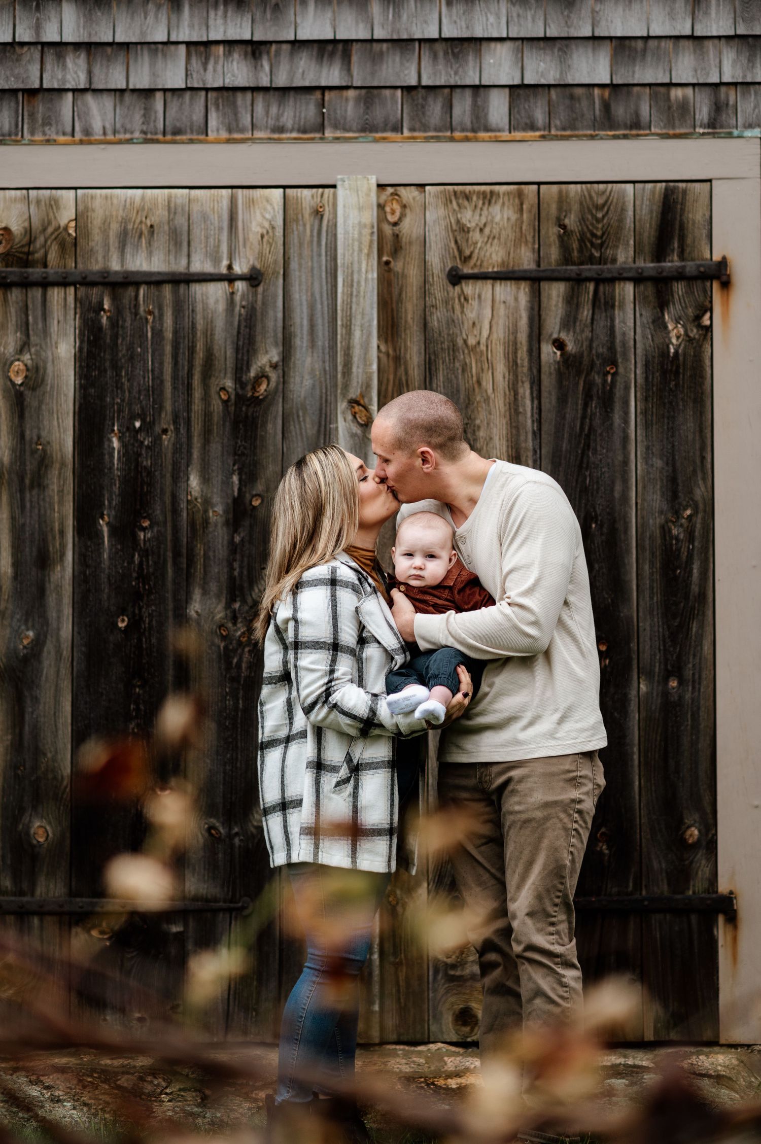 A romantic couple shares tender moments against a rustic wooden fence backdrop in a series of intimate photos.