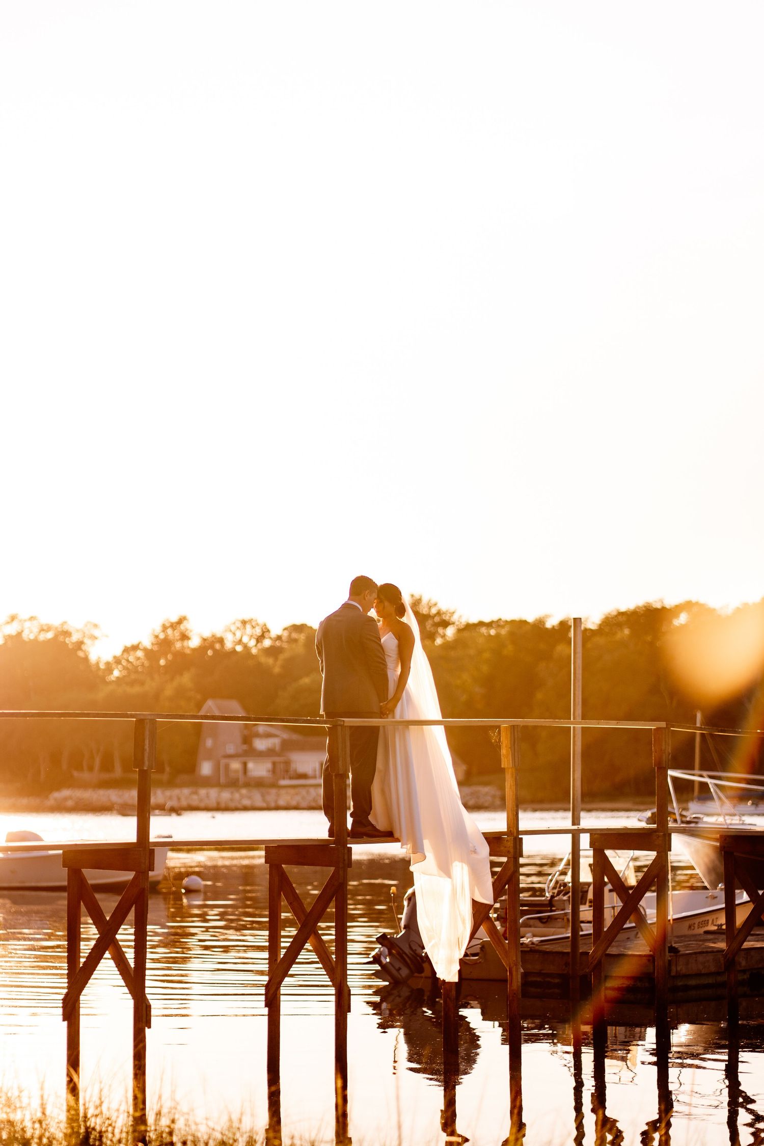 A silhouetted couple shares an intimate moment on a dock during golden hour sunset.