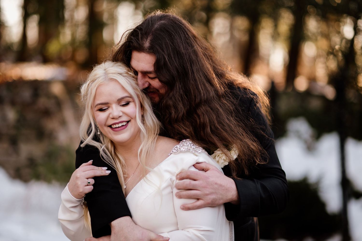 A couple shares a joyful moment together during their winter wedding celebration in a snowy outdoor setting.