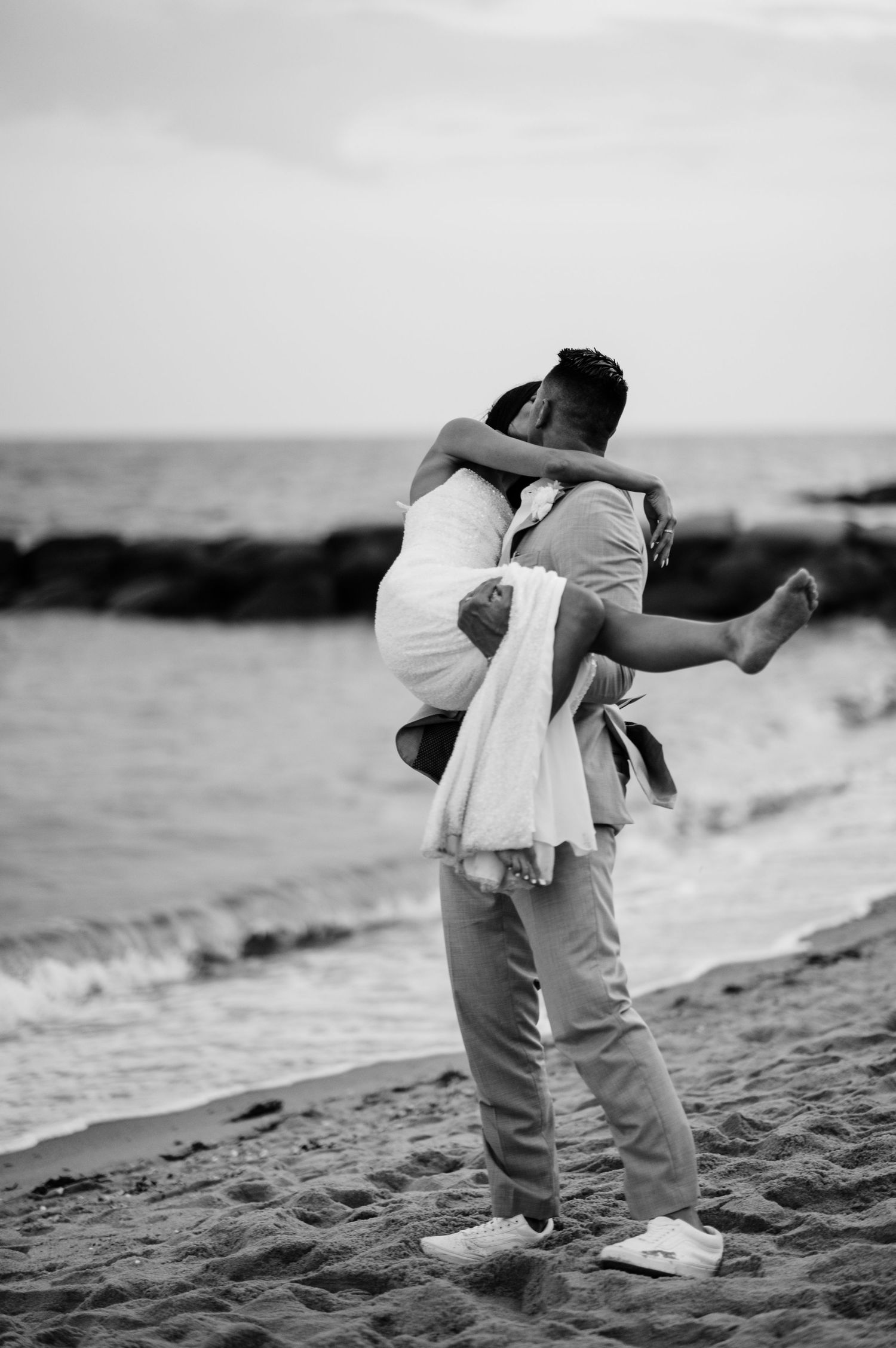 Black and white series of couple dancing playfully together on a beach at sunset.