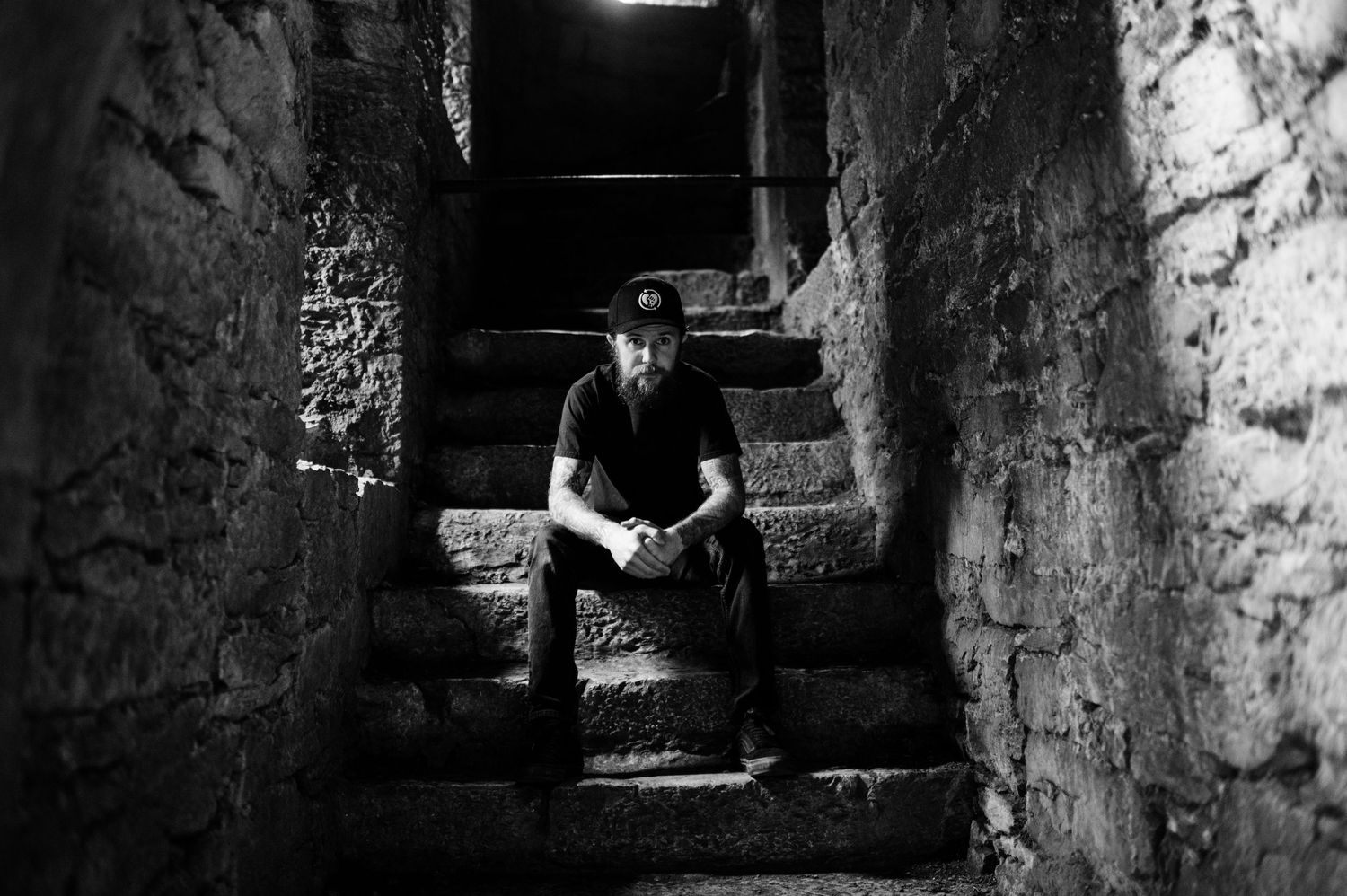 Black and white photographs show a person descending stone steps in an ancient underground tunnel or crypt.