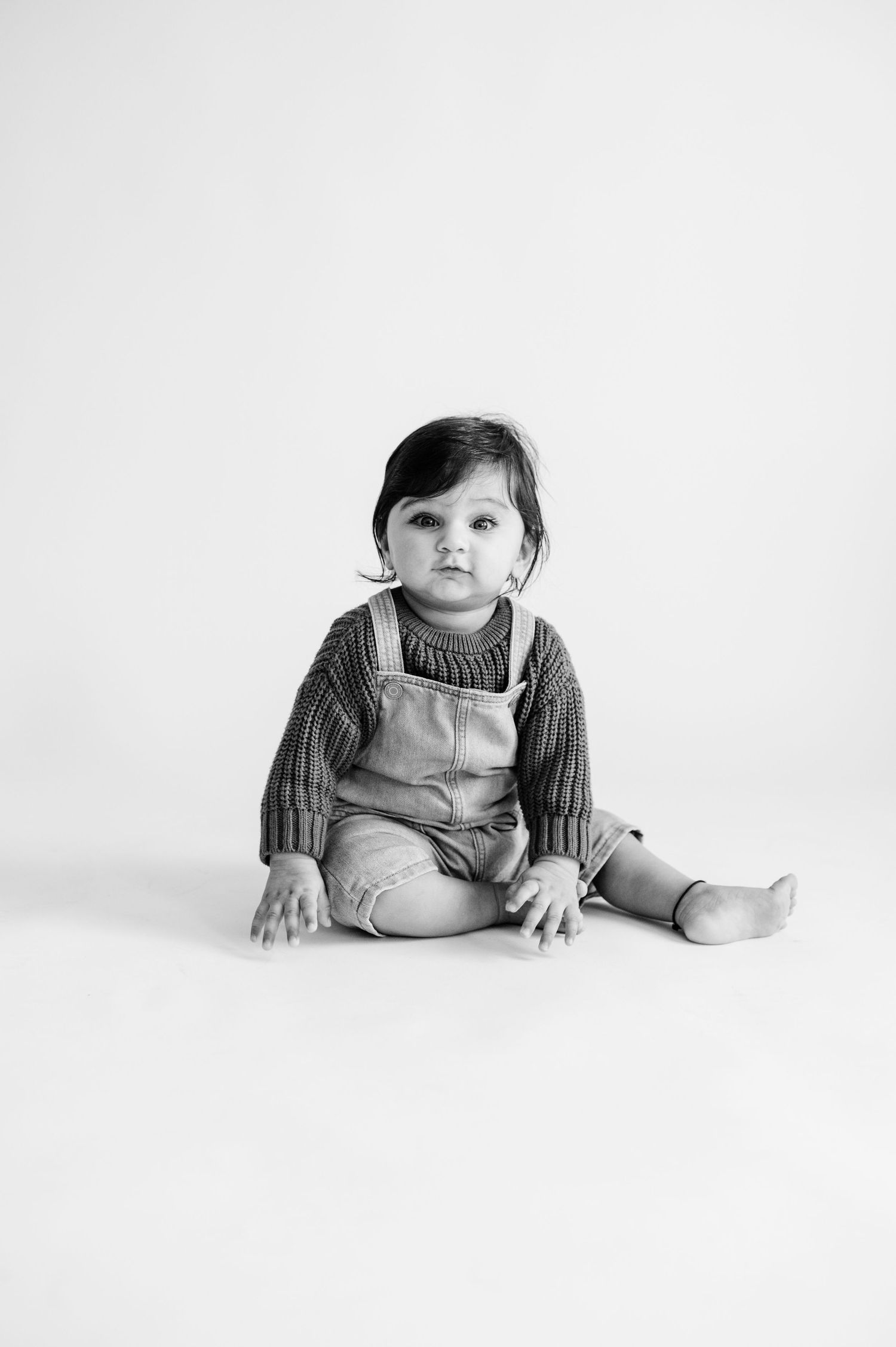 Black and white studio portraits of a baby crawling on white background.