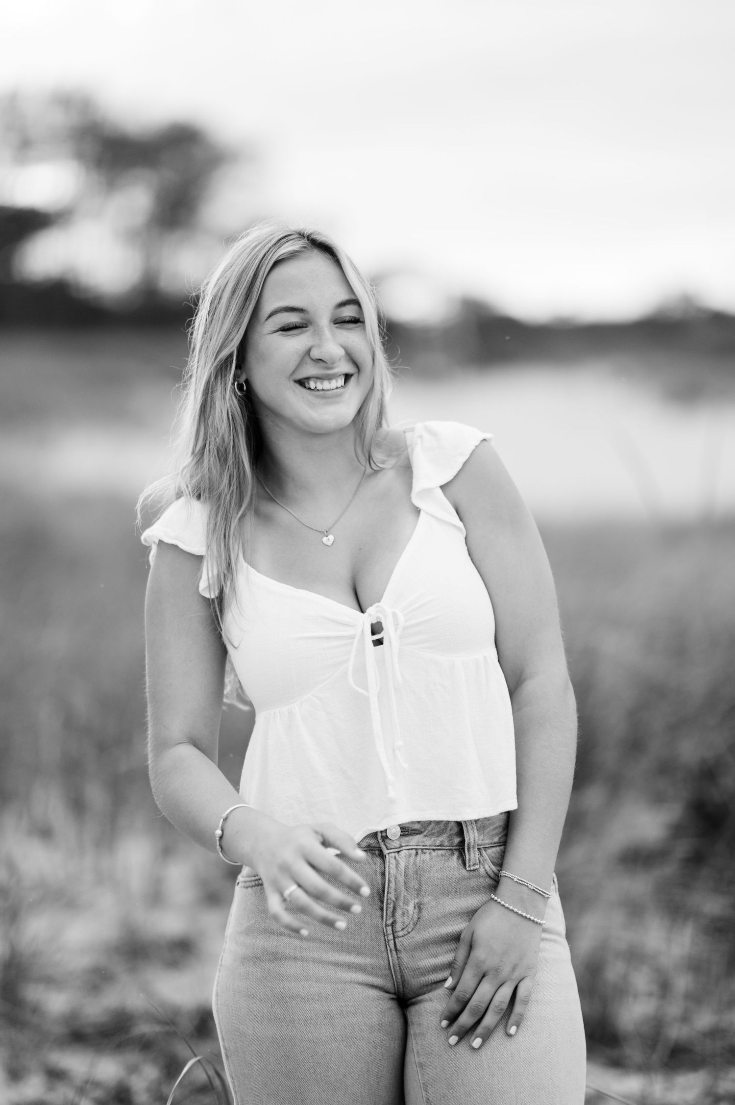 A series of black and white outdoor portraits showing someone wearing a white top and jeans in a natural setting.