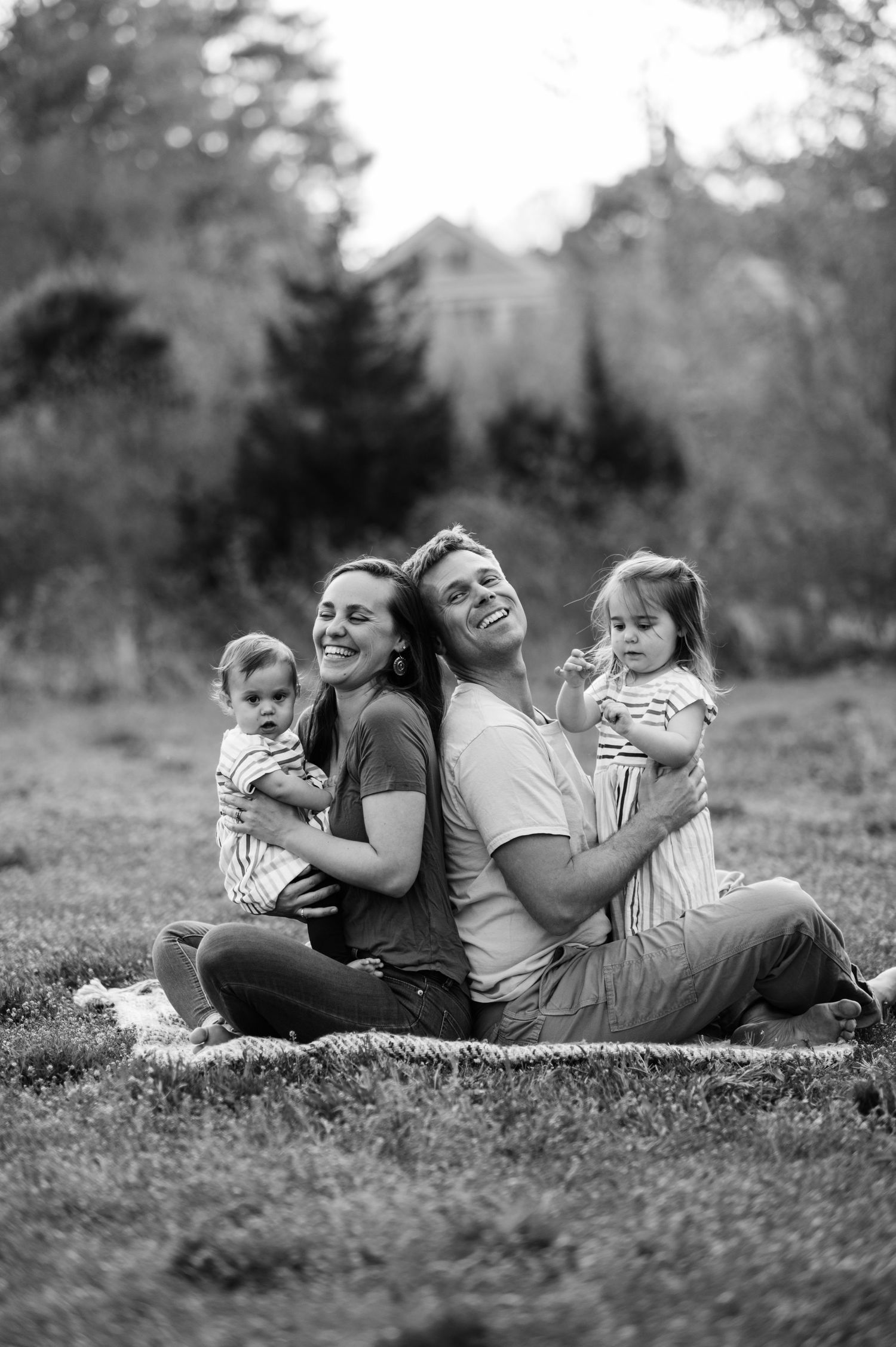 Family lying together on grass sharing joyful moments in black and white photography.