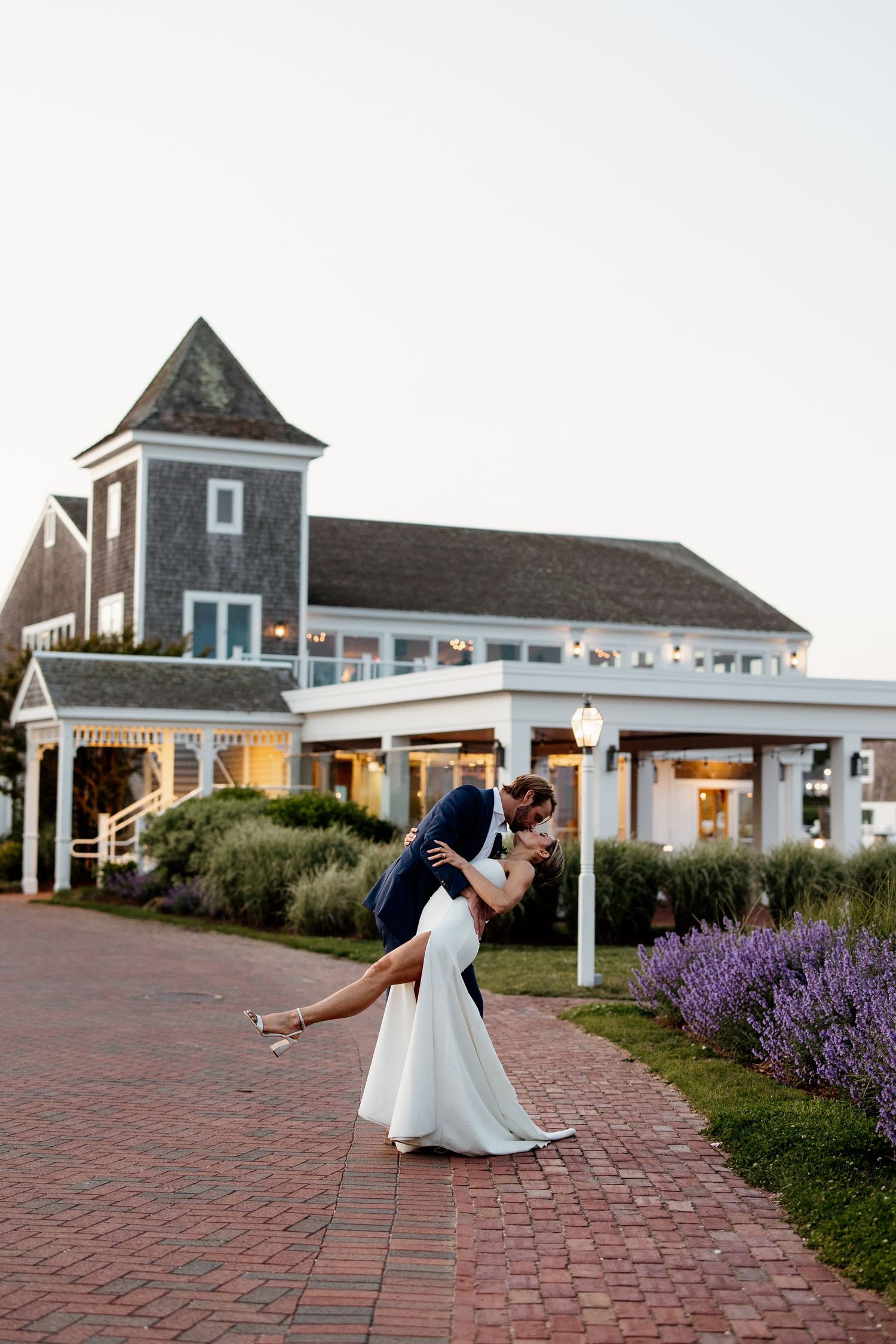 Couple dancing and dipping on a brick patio with coastal buildings in the background.