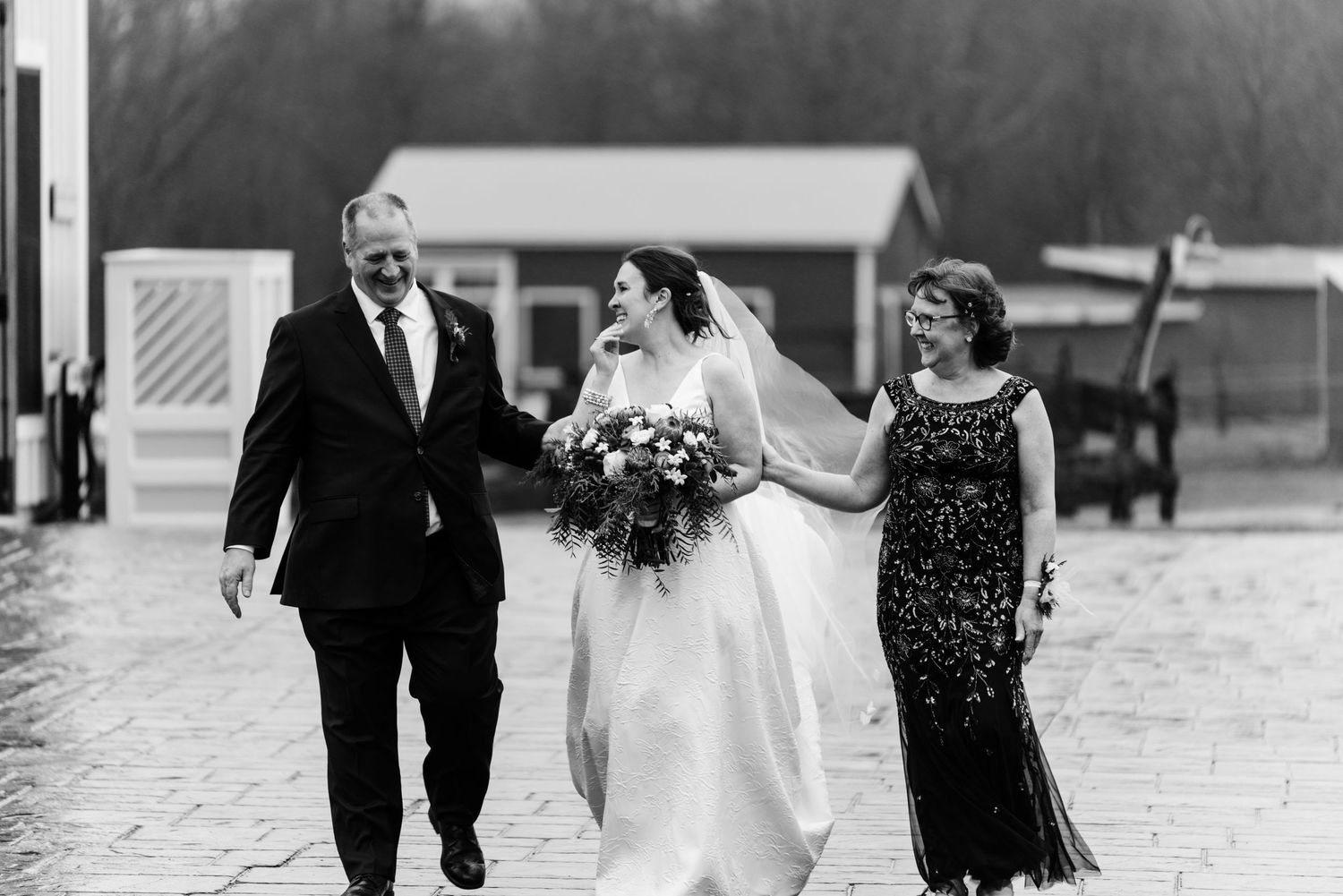 A black and white wedding photo captures a celebratory moment as a group walks together outdoors.