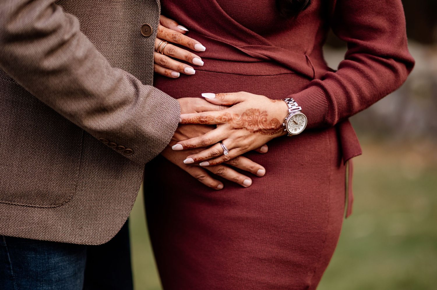 Close-up shots focusing on gentle hands touching a pregnant belly in burgundy sweater.