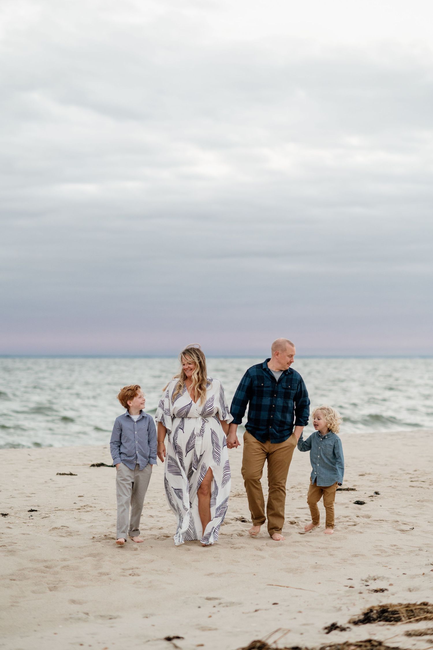 Family walking together along a peaceful beach shoreline during golden hour.