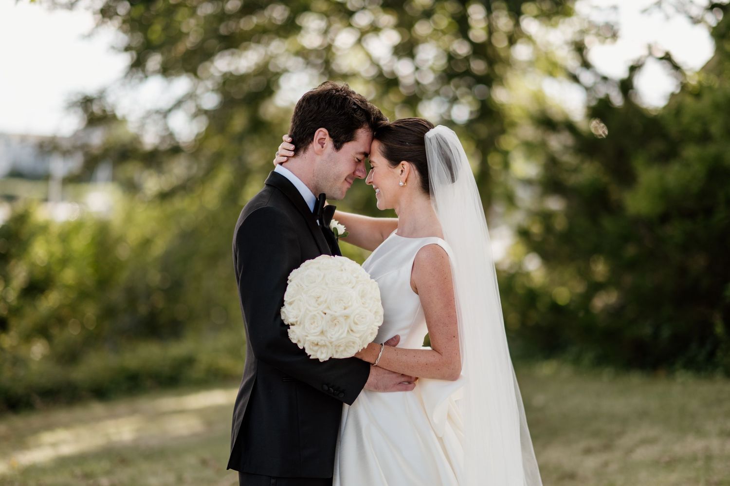 A romantic couple in wedding attire share intimate moments during an outdoor photo session in a natural setting.
