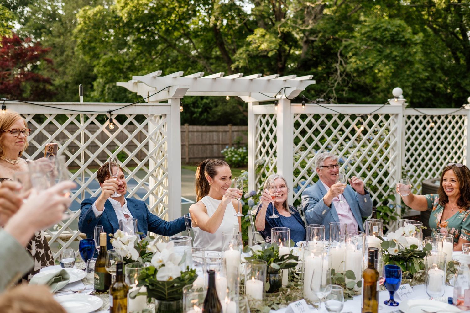 An elegant outdoor wedding reception setup with white lattice decorations and floral arrangements.
