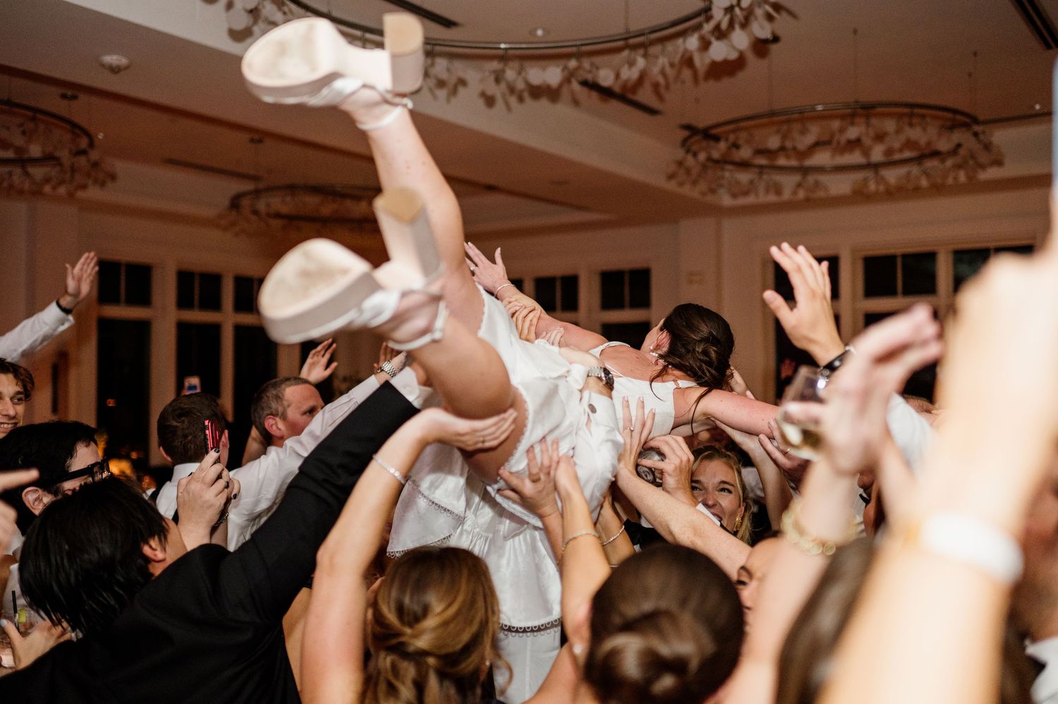 Guests dancing and celebrating with raised hands at a lively wedding reception.