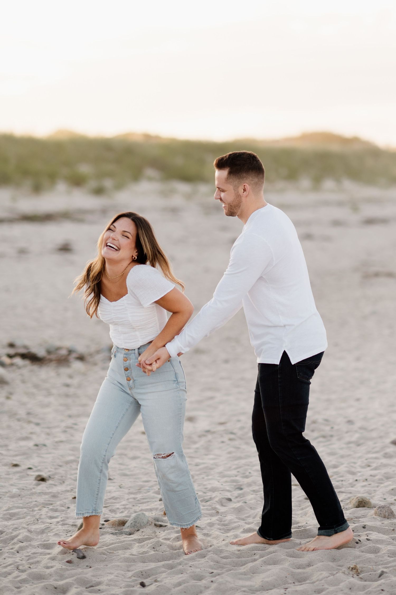Candid sequence of a couple playing and laughing together on a sandy beach at sunset.