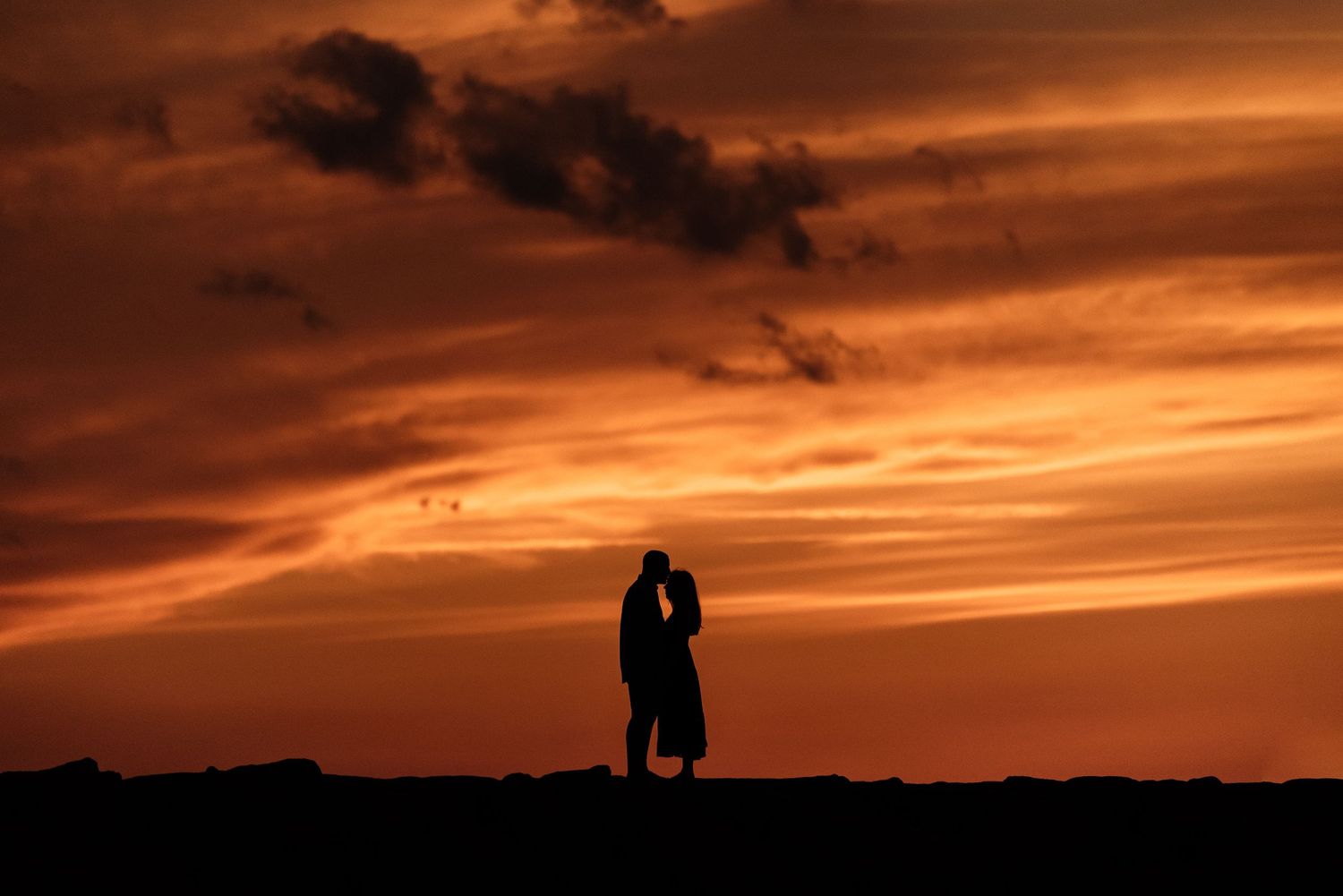 Dramatic orange and red sunset sky with silhouettes creating a romantic atmosphere.