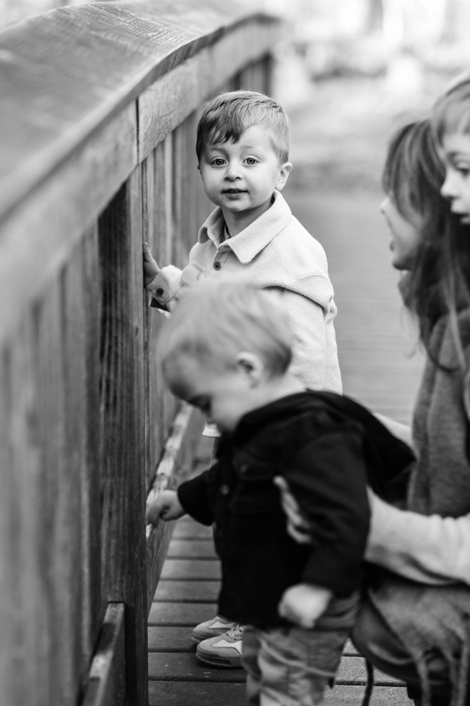 Black and white sequence of playful moments along a wooden railing outdoors.