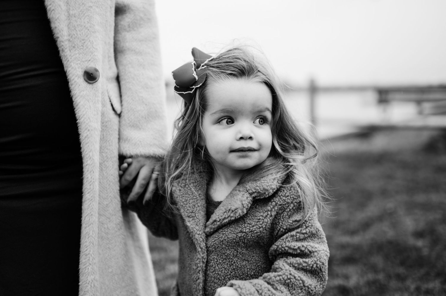 Black and white portrait of child in winter coat against moody backdrop.