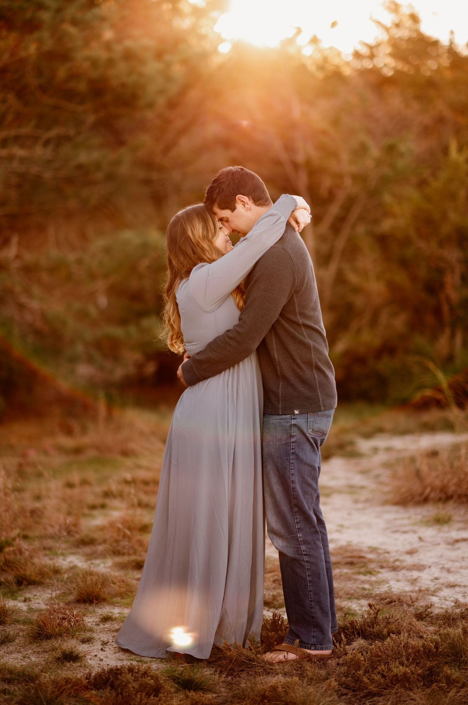Couple sharing an intimate moment at sunset in a natural outdoor setting.