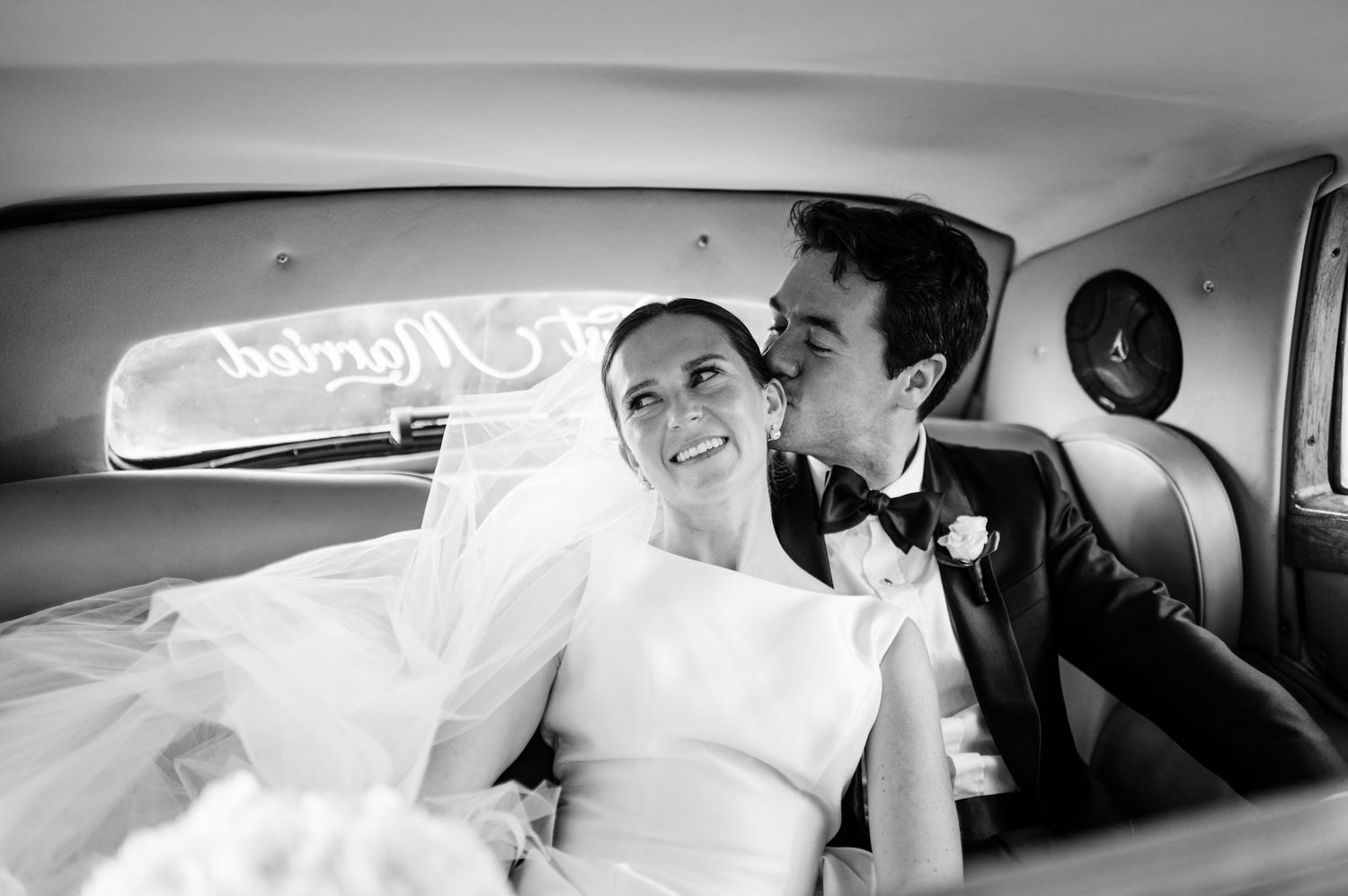 Wedding party riding together in classic car interior.