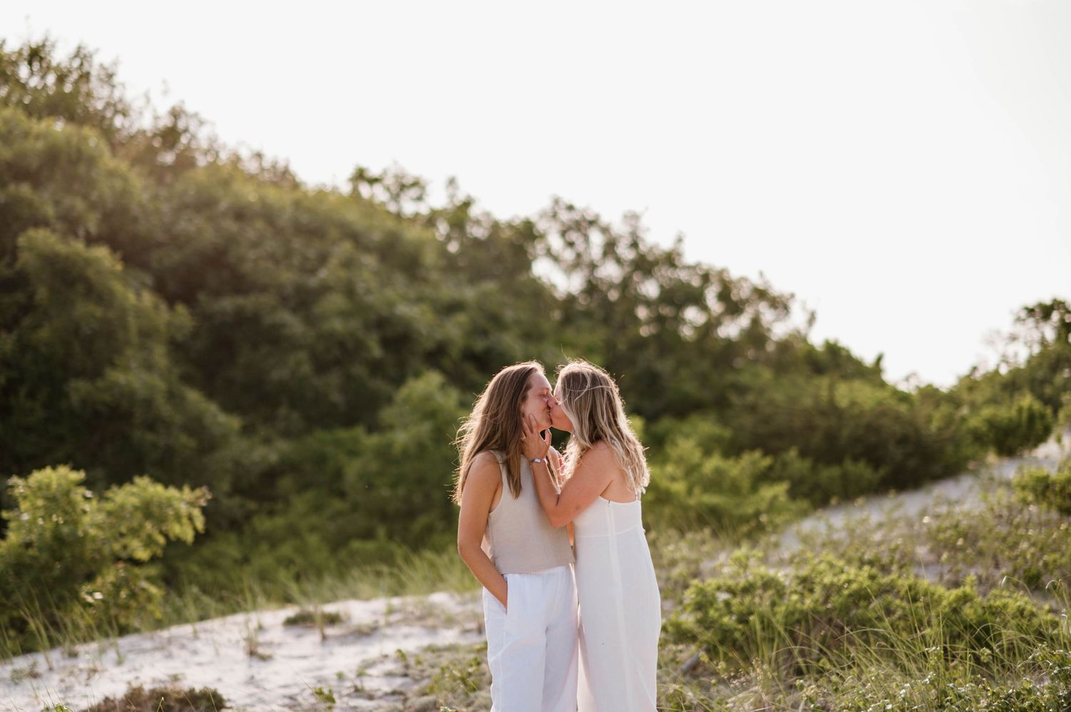 A couple walks hand in hand along a scenic coastal path surrounded by greenery.