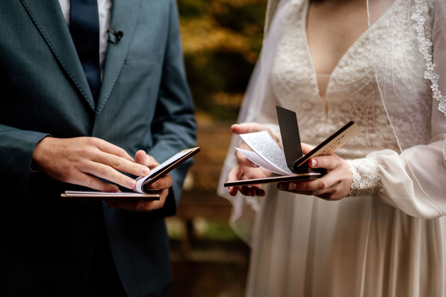 Close-up view of hands exchanging wedding vows and signing marriage documents during an indoor ceremony.