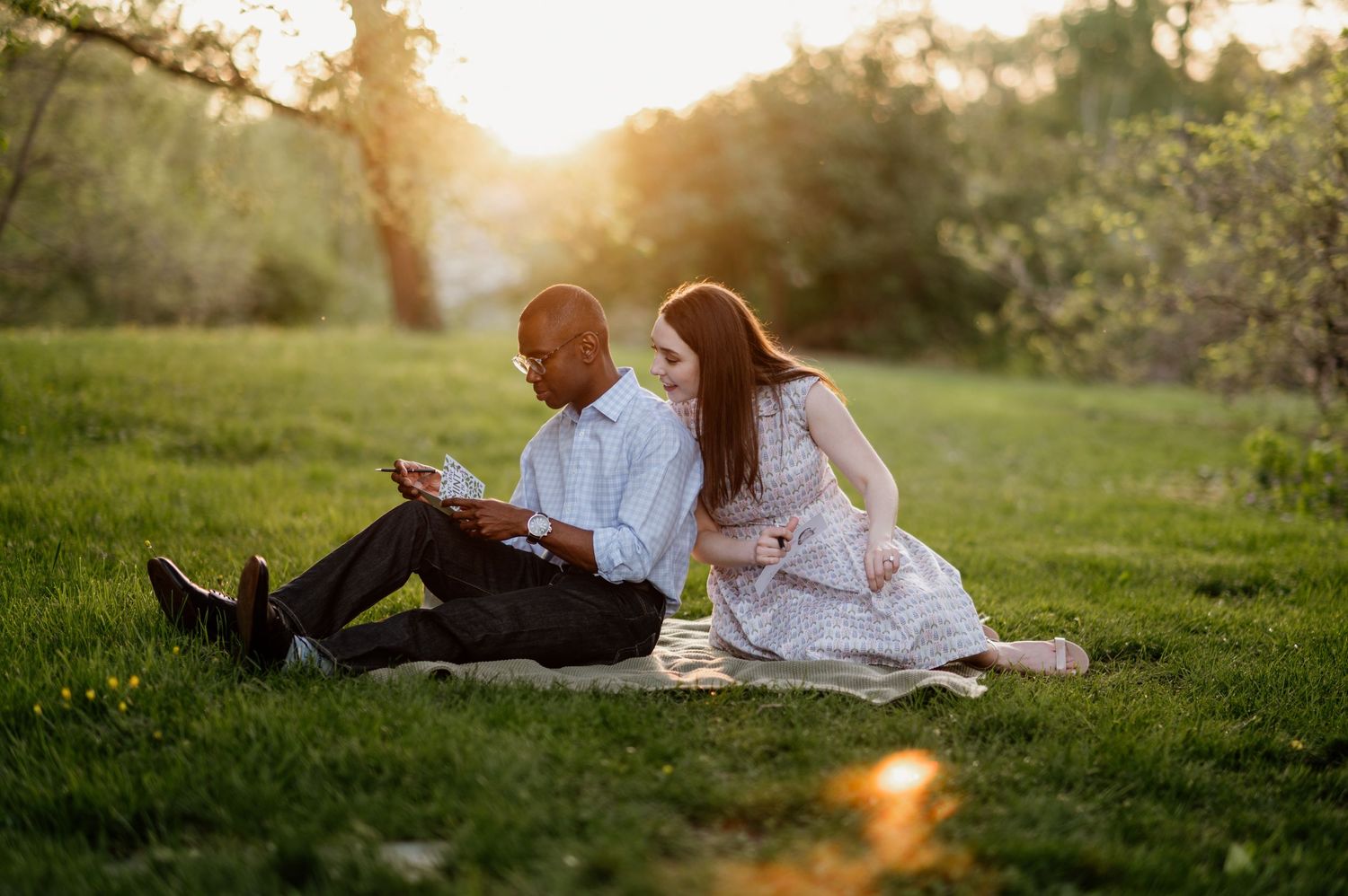 Couple lounging on grass during golden hour sunset.