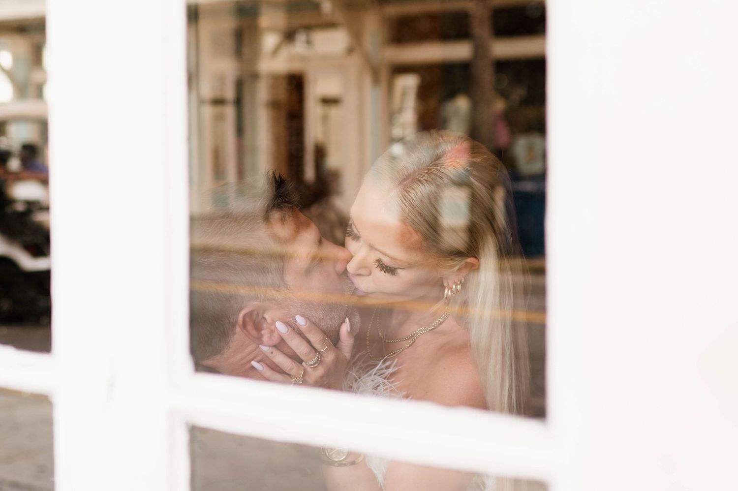 Through a window reflection, a dreamy vintage-style portrait shows someone sipping from a coffee cup.