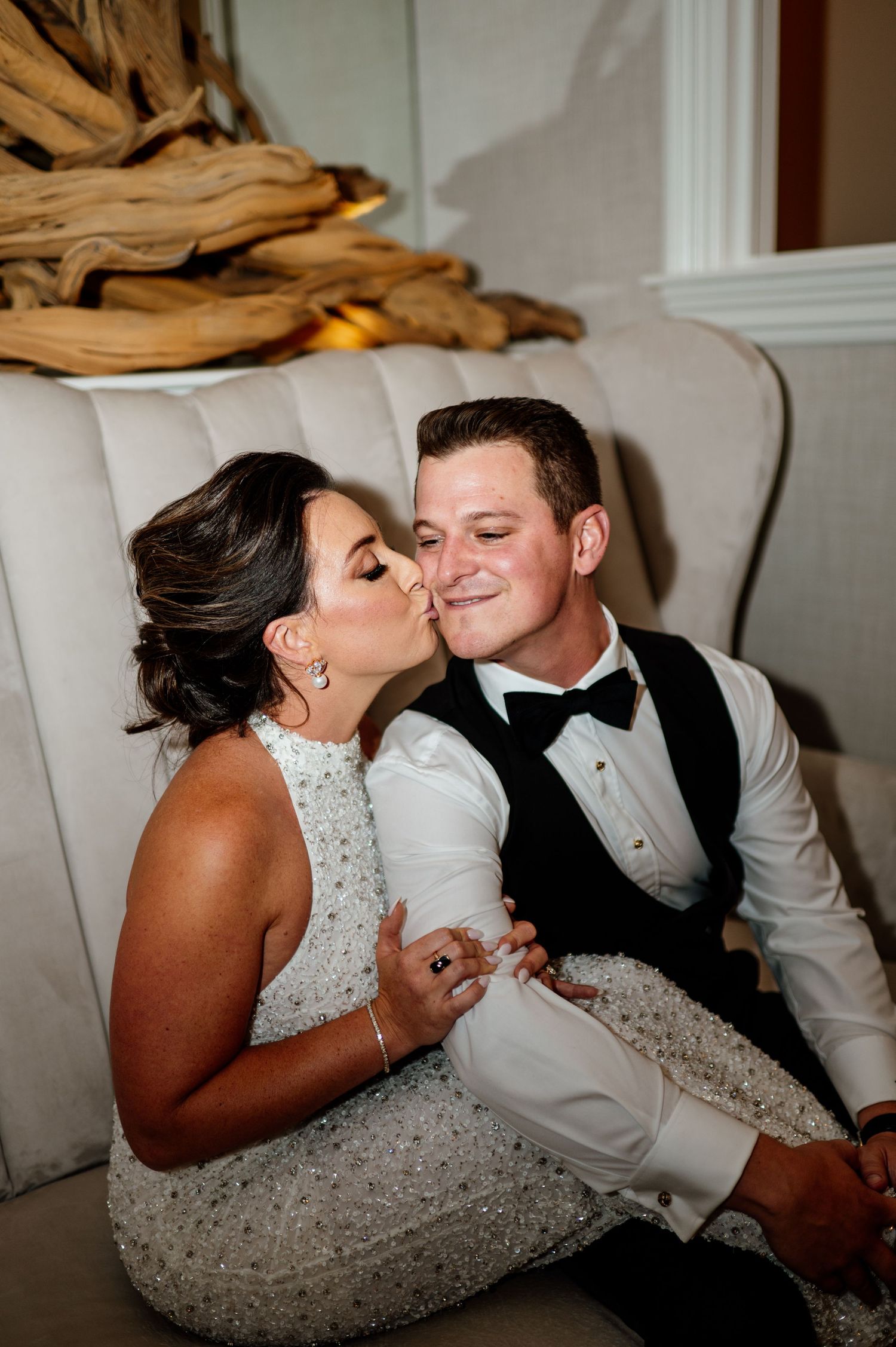 Romantic couple in formal attire sharing intimate moments on a white couch.