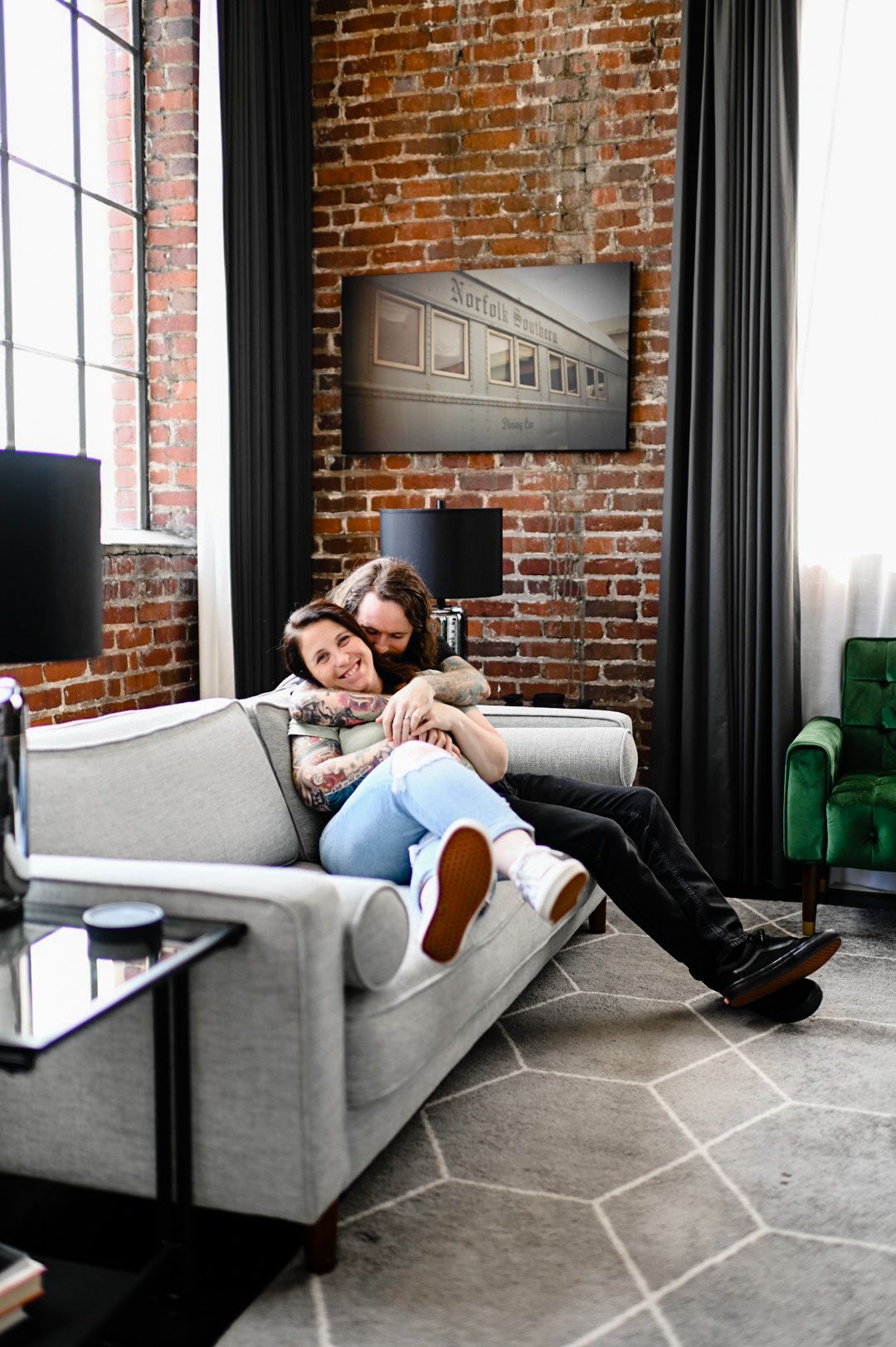 Four connected images show someone lounging and working on a gray couch against an exposed brick wall in an office space.